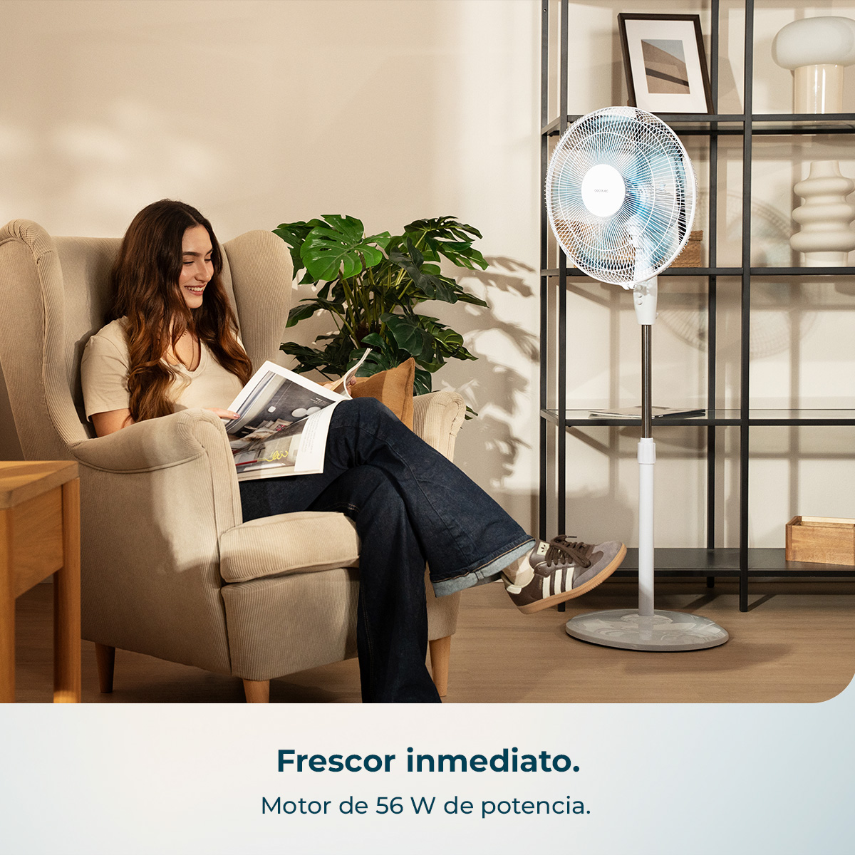 Una mujer lee en un sillón, un ventilador está cerca.