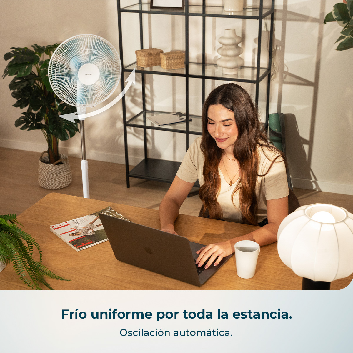 Una mujer trabaja en un portátil, un ventilador oscila a izquierda y derecha.