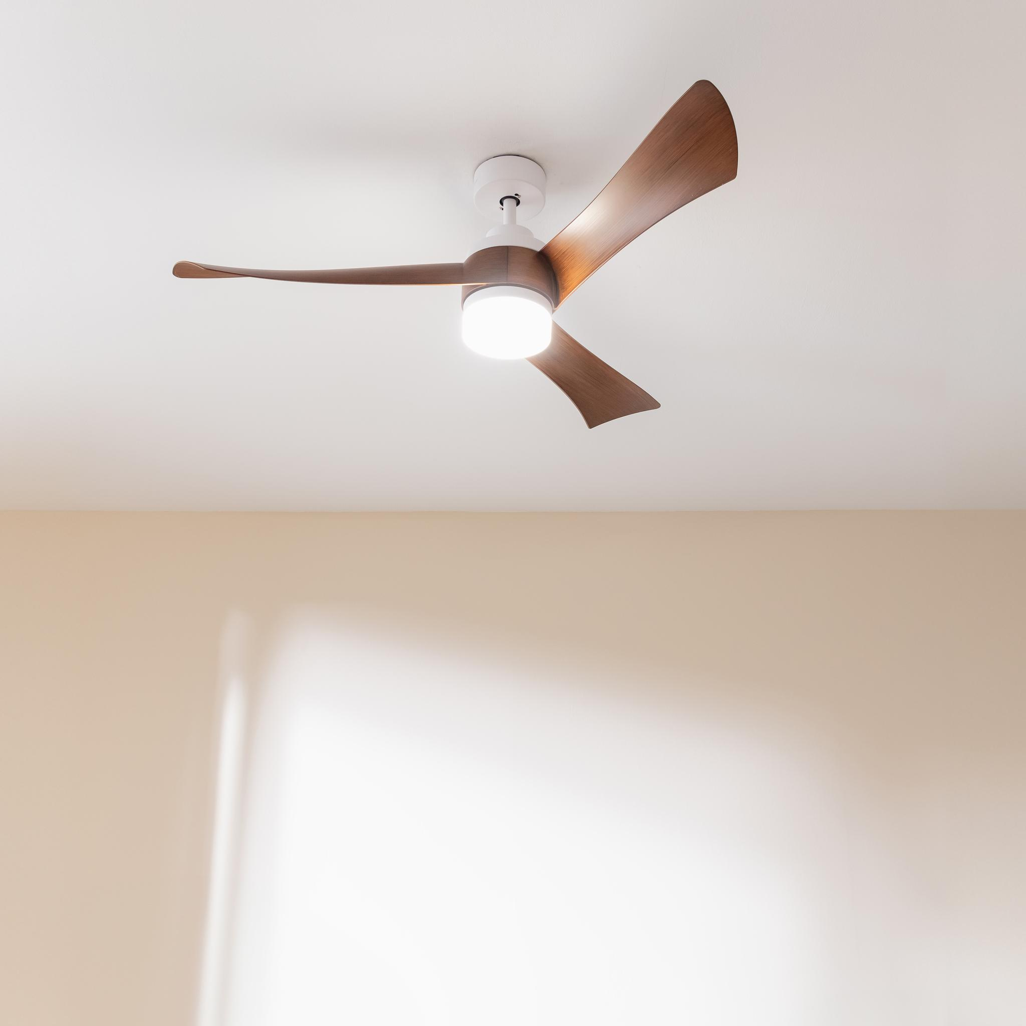 Un ventilador de techo moderno con tres aspas de madera y luz integrada.