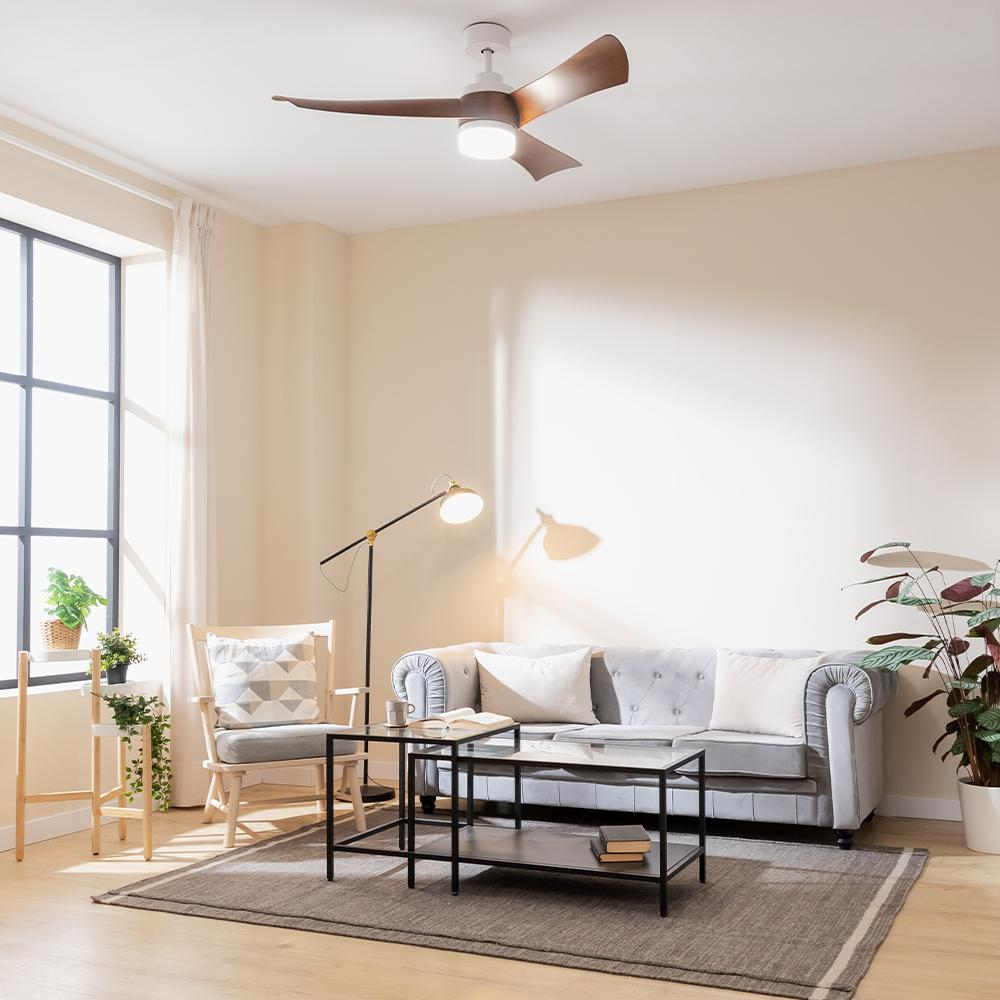 Una sala de estar luminosa con sofá, mesa de centro, lámpara y ventilador de techo.