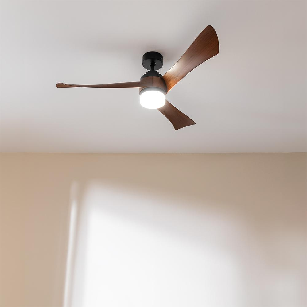 Un ventilador de techo moderno con tres aspas de madera y luz integrada.