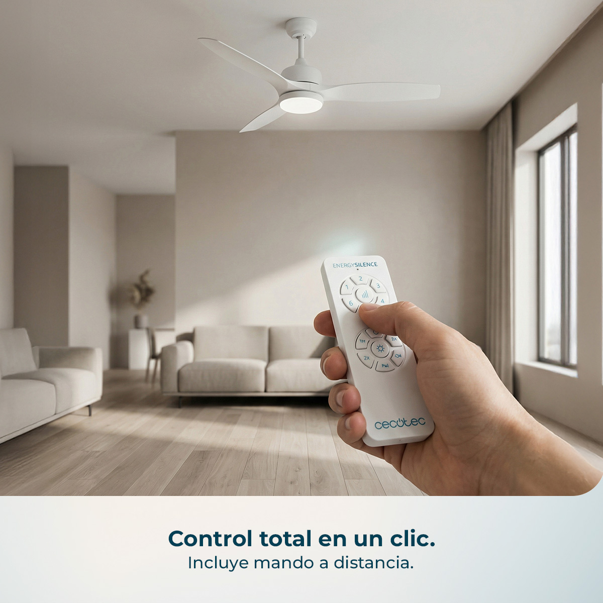 Una mano sostiene un mando a distancia delante de un ventilador de techo.