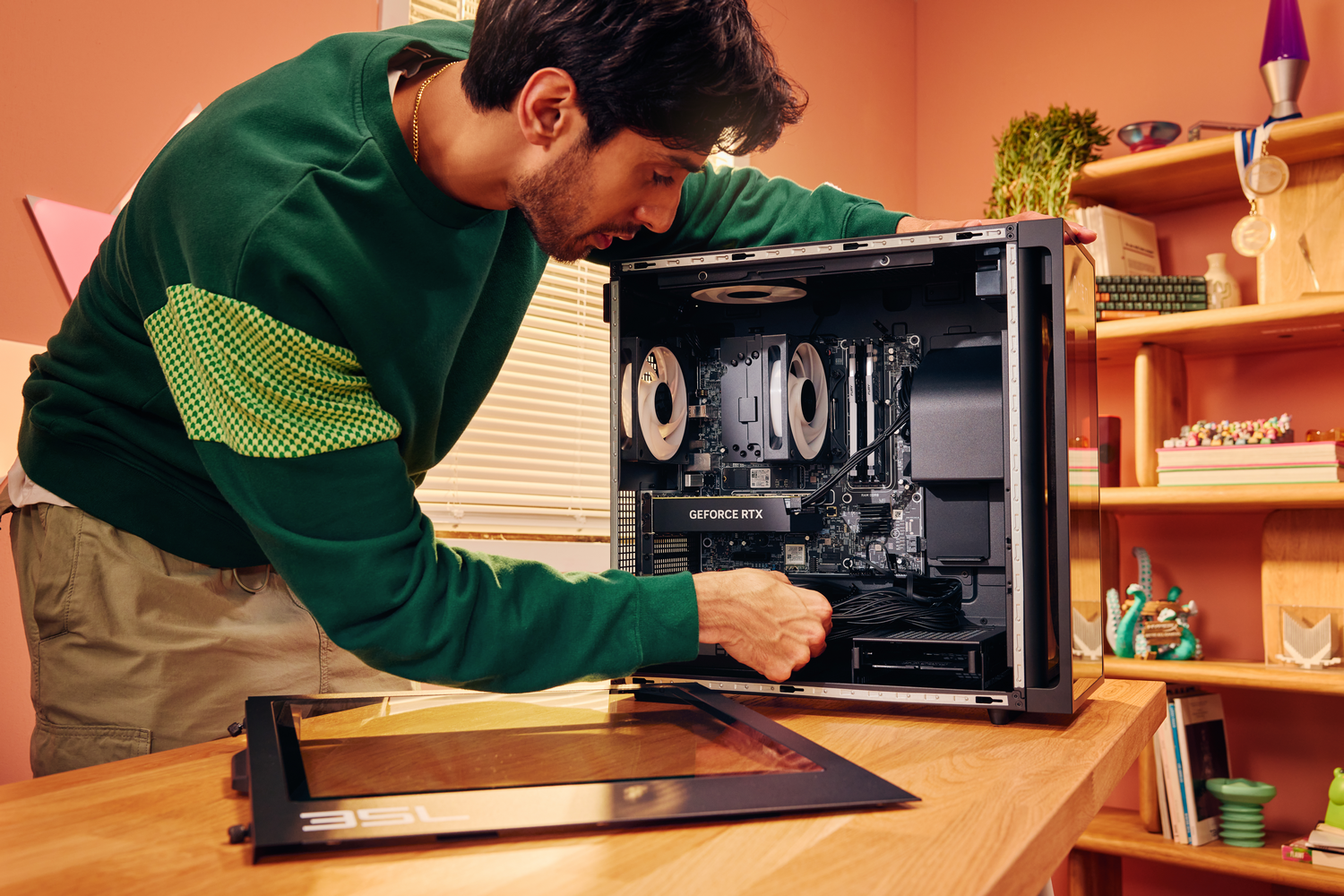 Hombre con suéter verde armando PC. Conectando cables. Escritorio de madera.