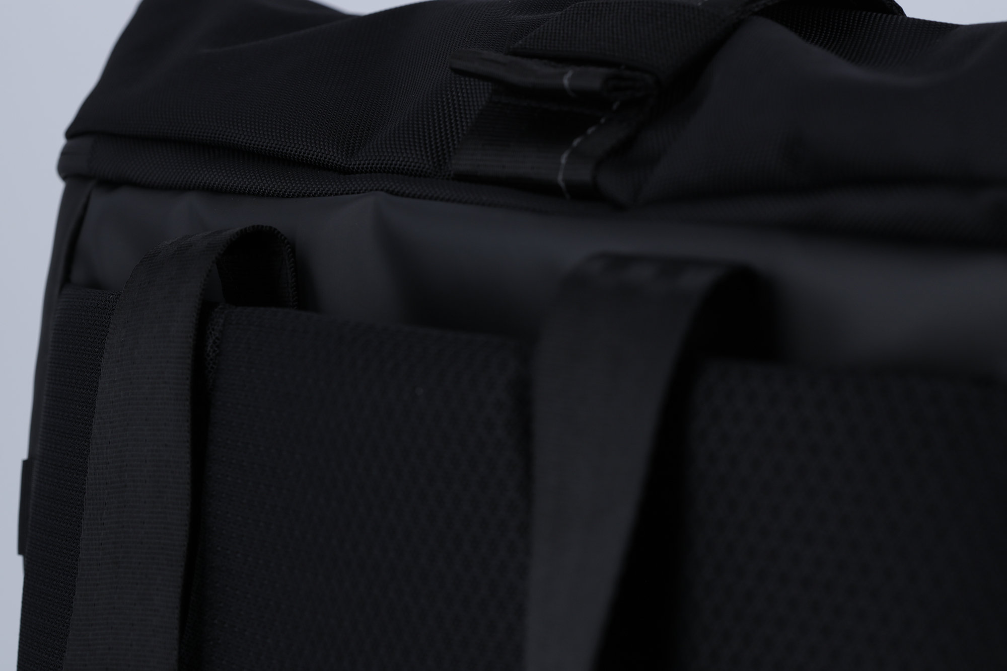 Nahaufnahme eines schwarzen Rucksacks mit gepolsterten Trägern und texturiertem Stoff.