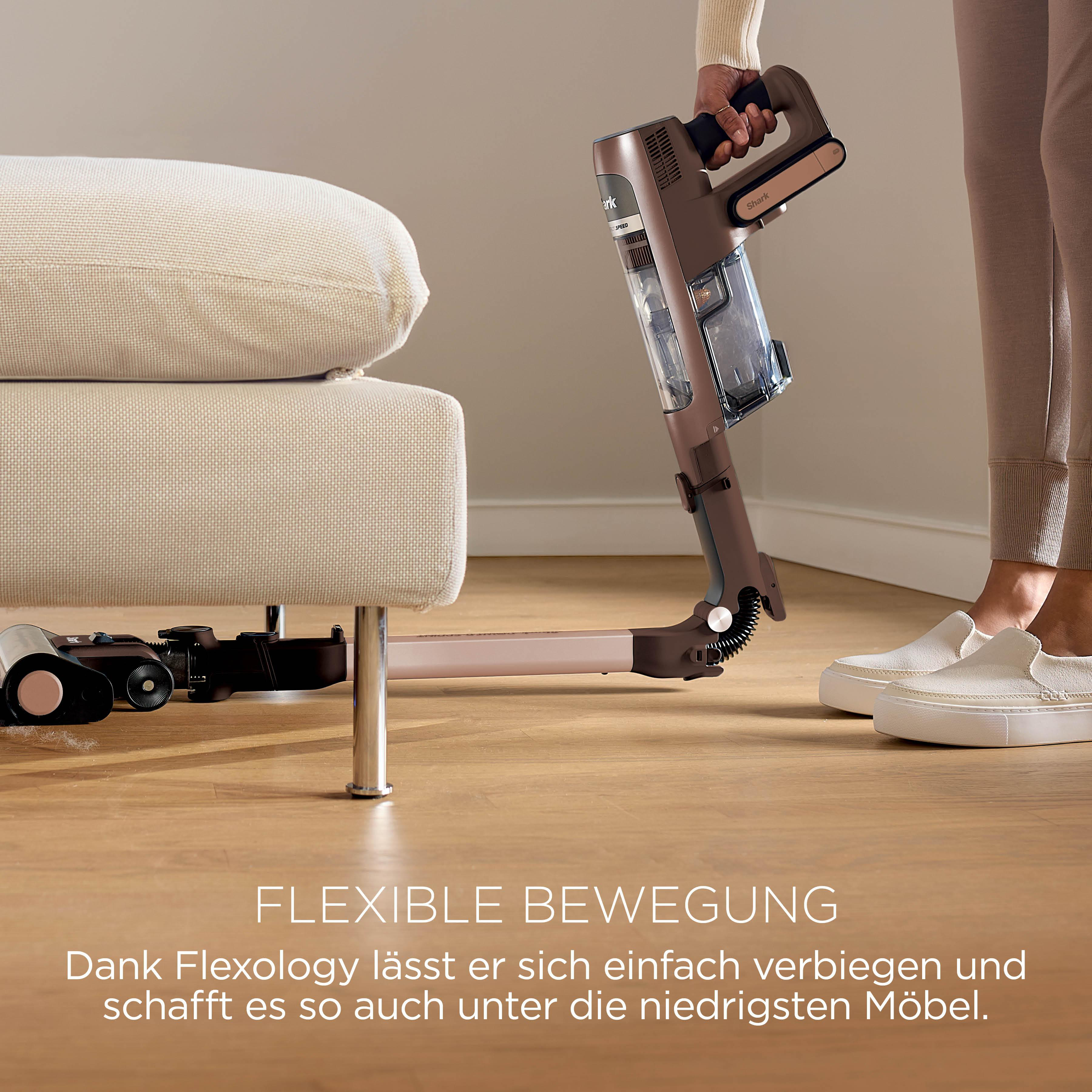 Ein Staubsauger wird unter ein Sofa gehalten, um die Flexibilität zu zeigen.