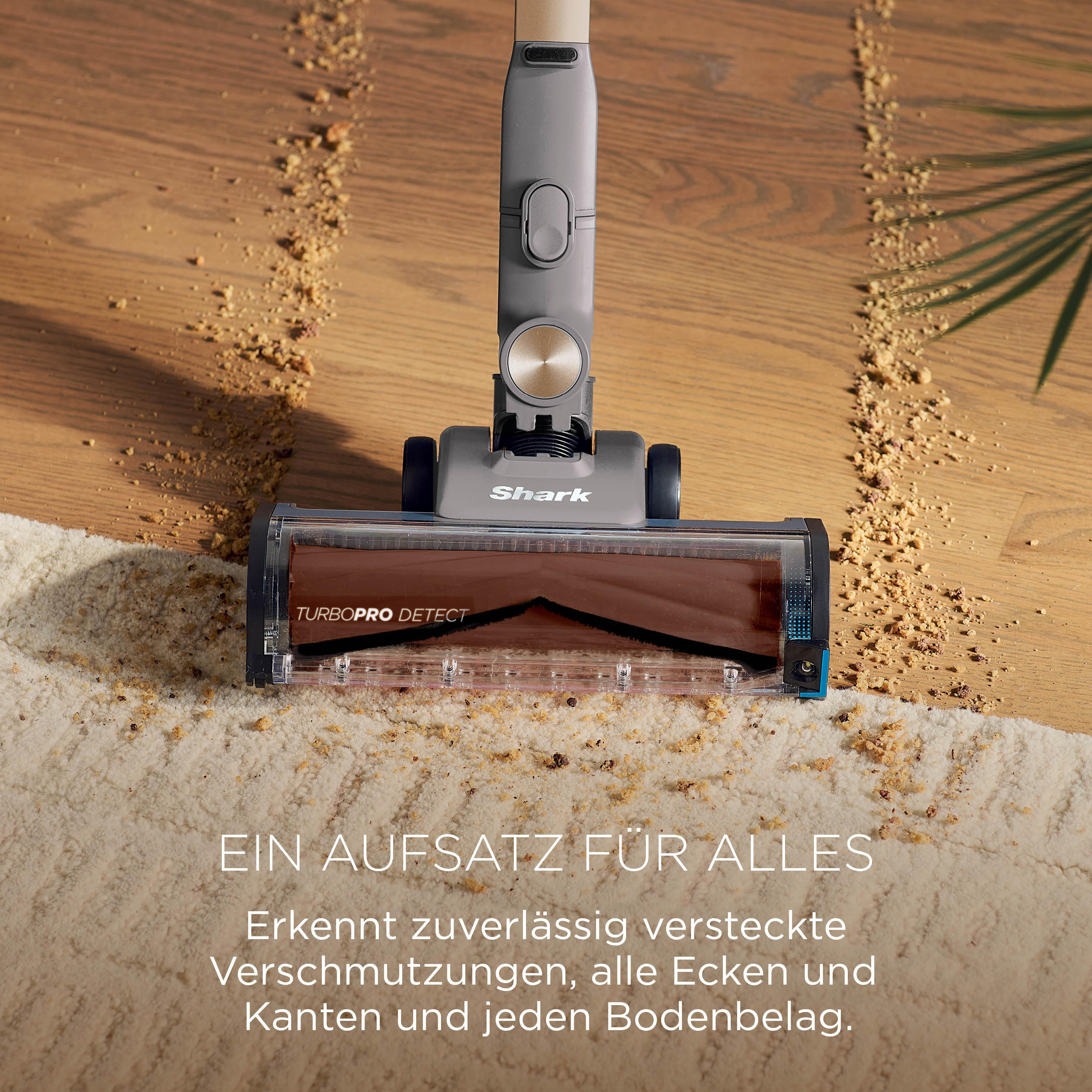 Staubsaugeraufsatz auf Teppich und Holzboden mit Krümeln.