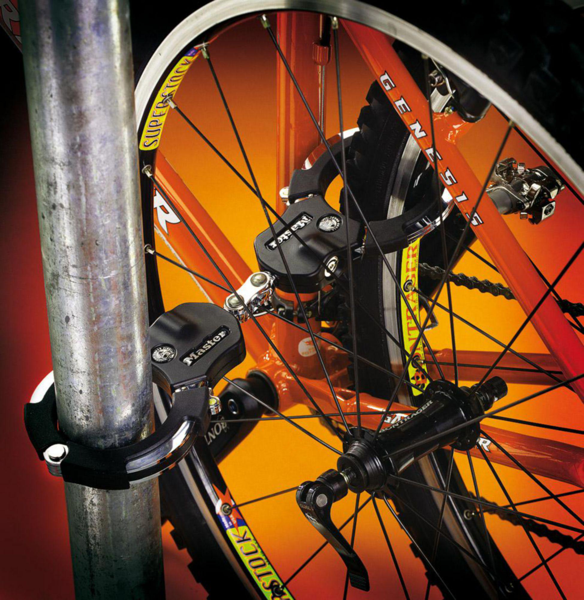 Ein Fahrradschloss sichert ein orangefarbenes Fahrrad an einer Metallstange.