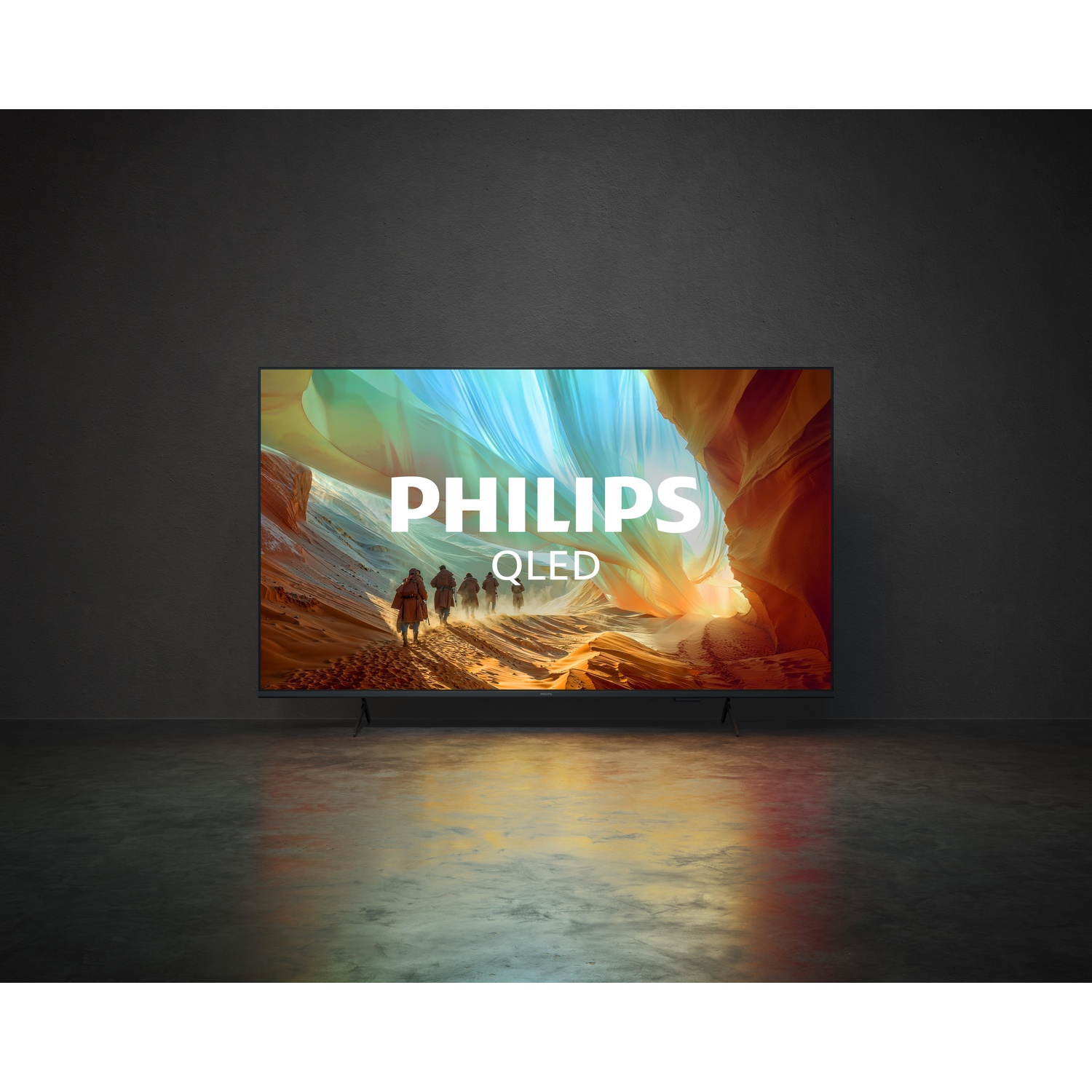 A Philips OLED TV in a dark room displaying a desert landscape.