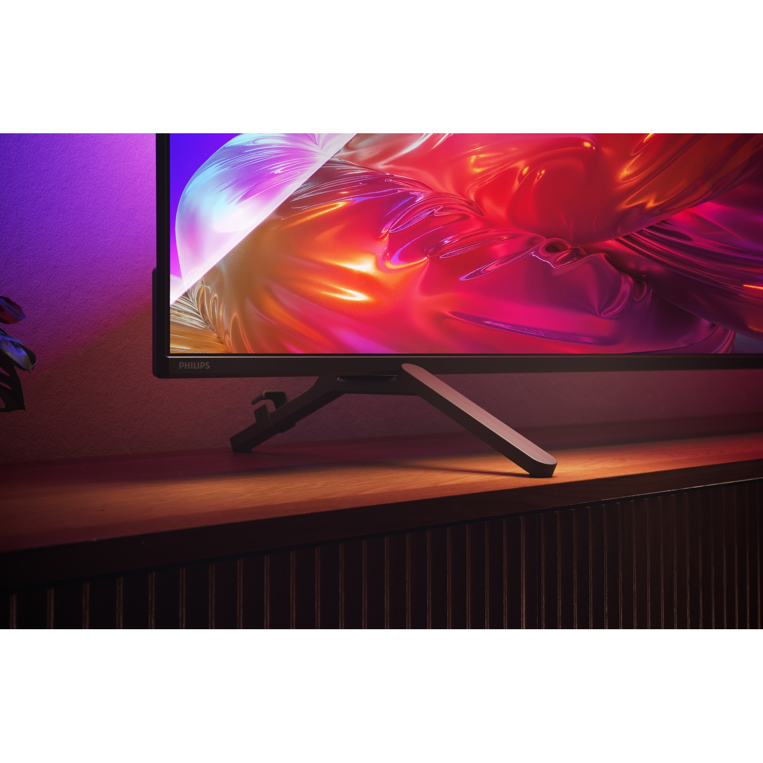 Een moderne Philips monitor met levendige abstracte achtergrond op een houten oppervlak.