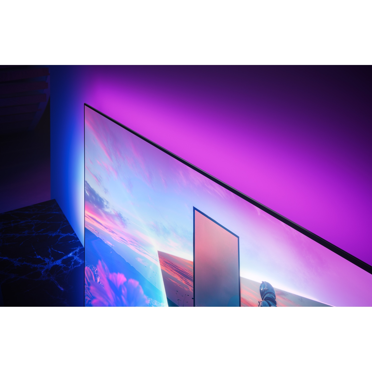 Een moderne tv met Ambilight gloeit paars en blauw. Het scherm toont een landschap.