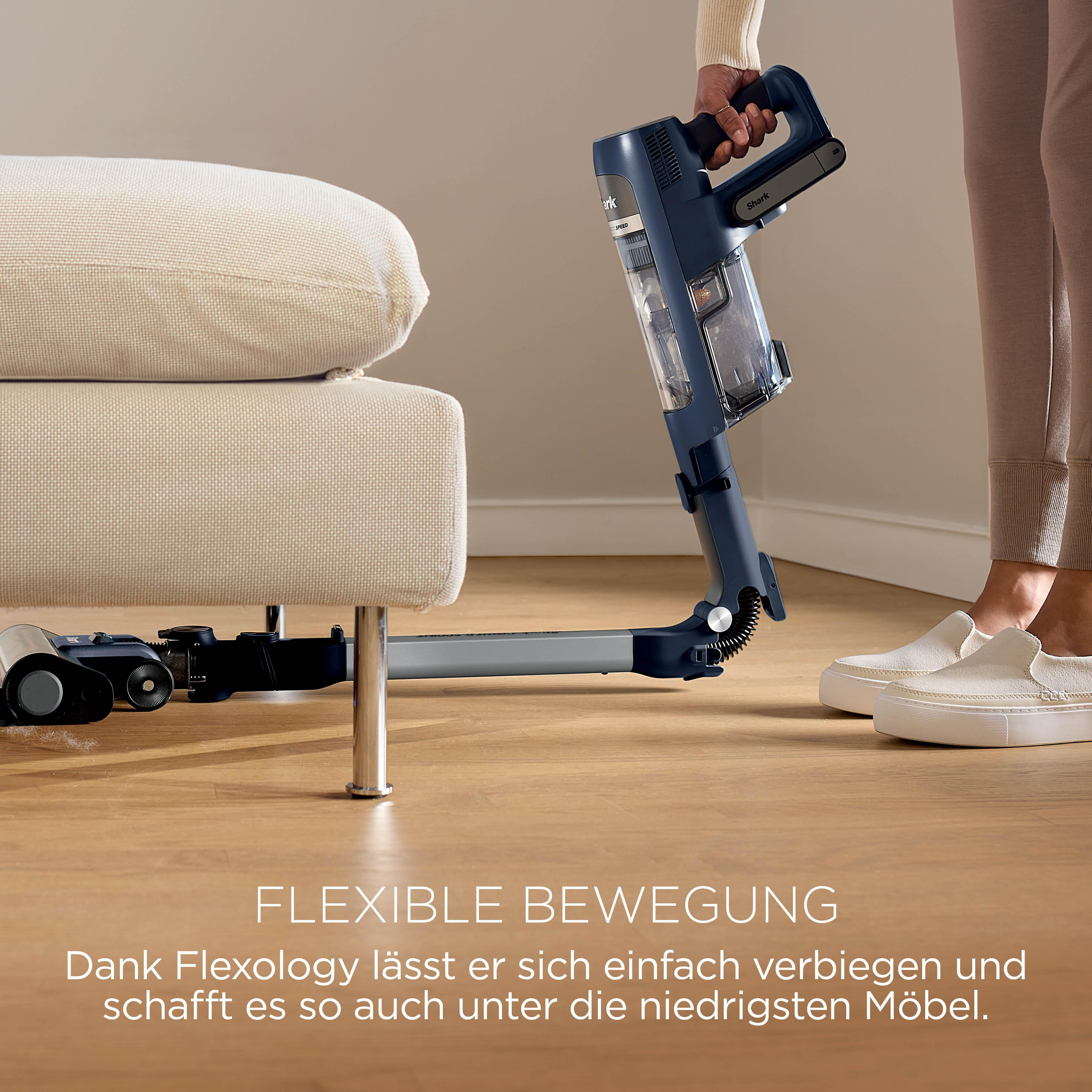 Ein dunkelblauer Handstaubsauger wird unter einem hellen Sofa benutzt.
