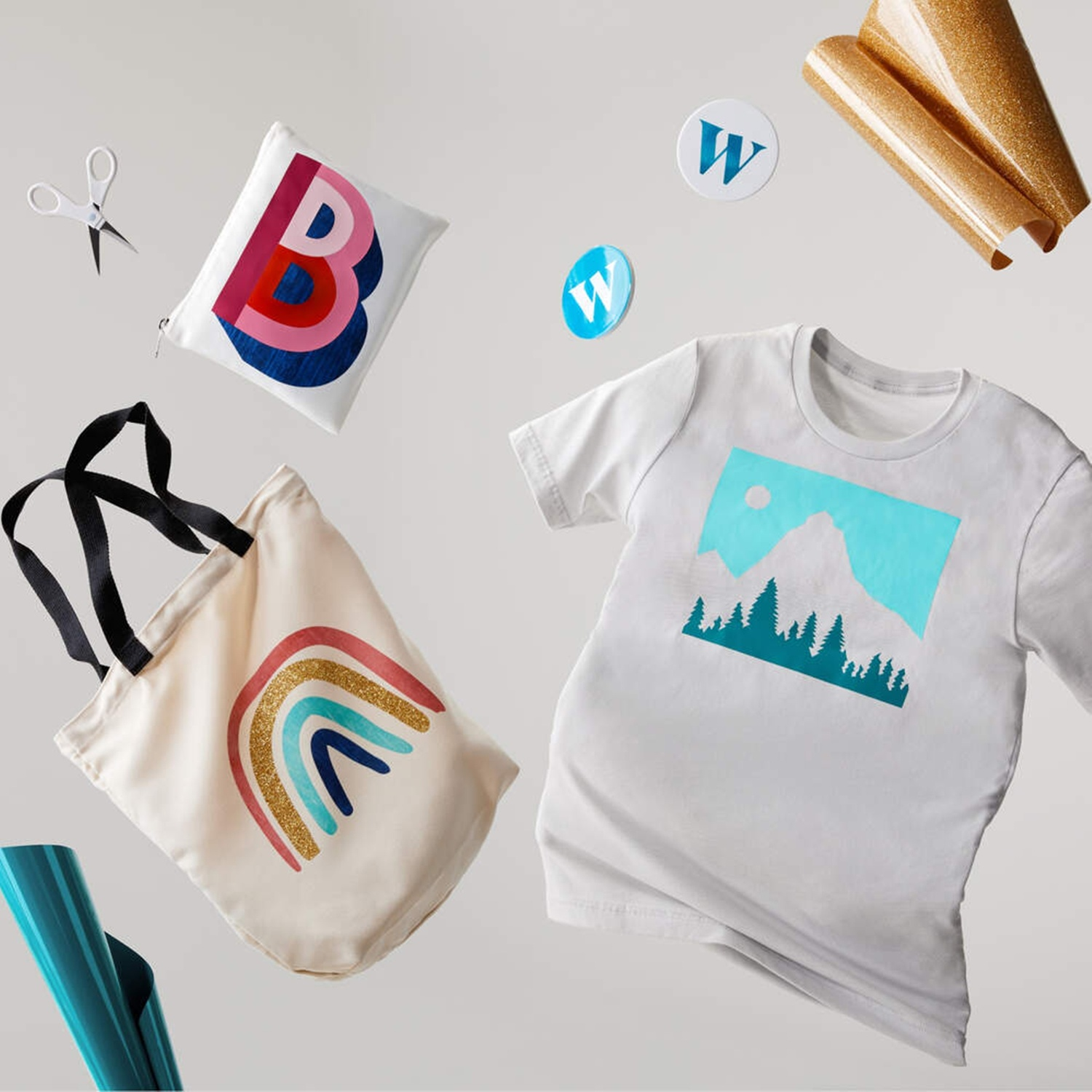 Forbici, borsa con B, t-shirt con motivo montano, rotoli di stoffa, adesivi.