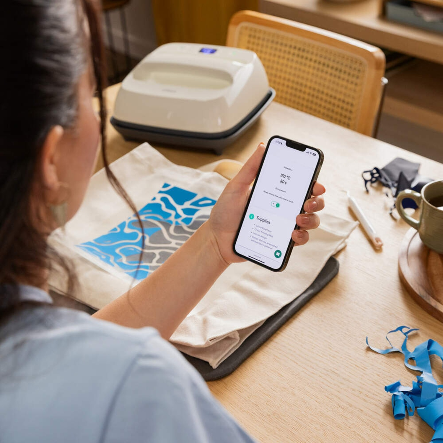 Una donna tiene uno smartphone con un'app, che mostra una pressa a caldo e una borsa.
