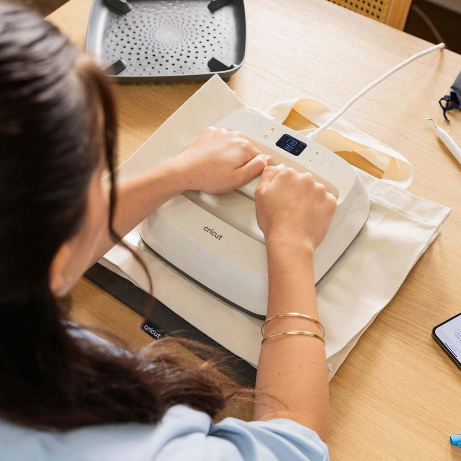 Una donna usa una pressa a caldo su una borsa con display digitale.
