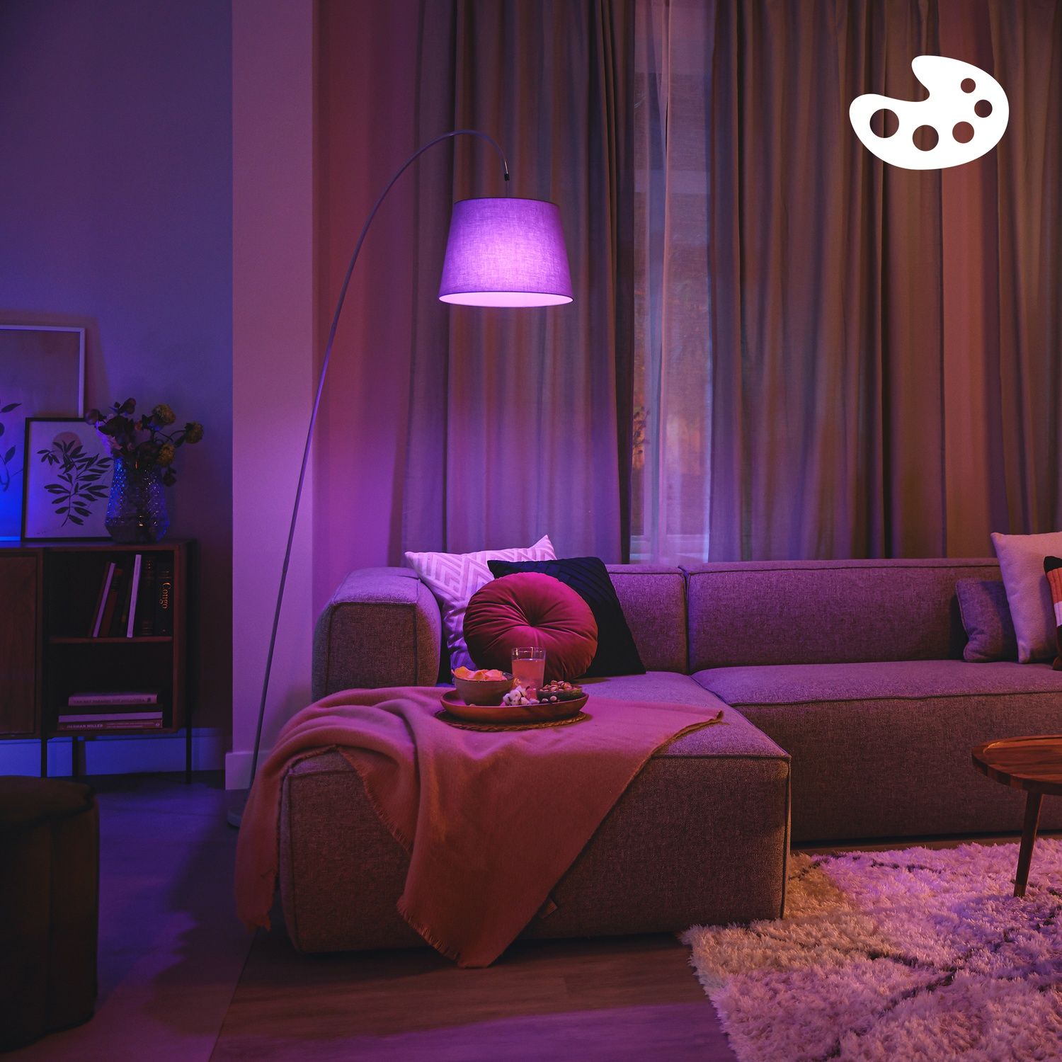 Un salon confortable avec canapé, tapis, lampadaire et collations sur plateau.