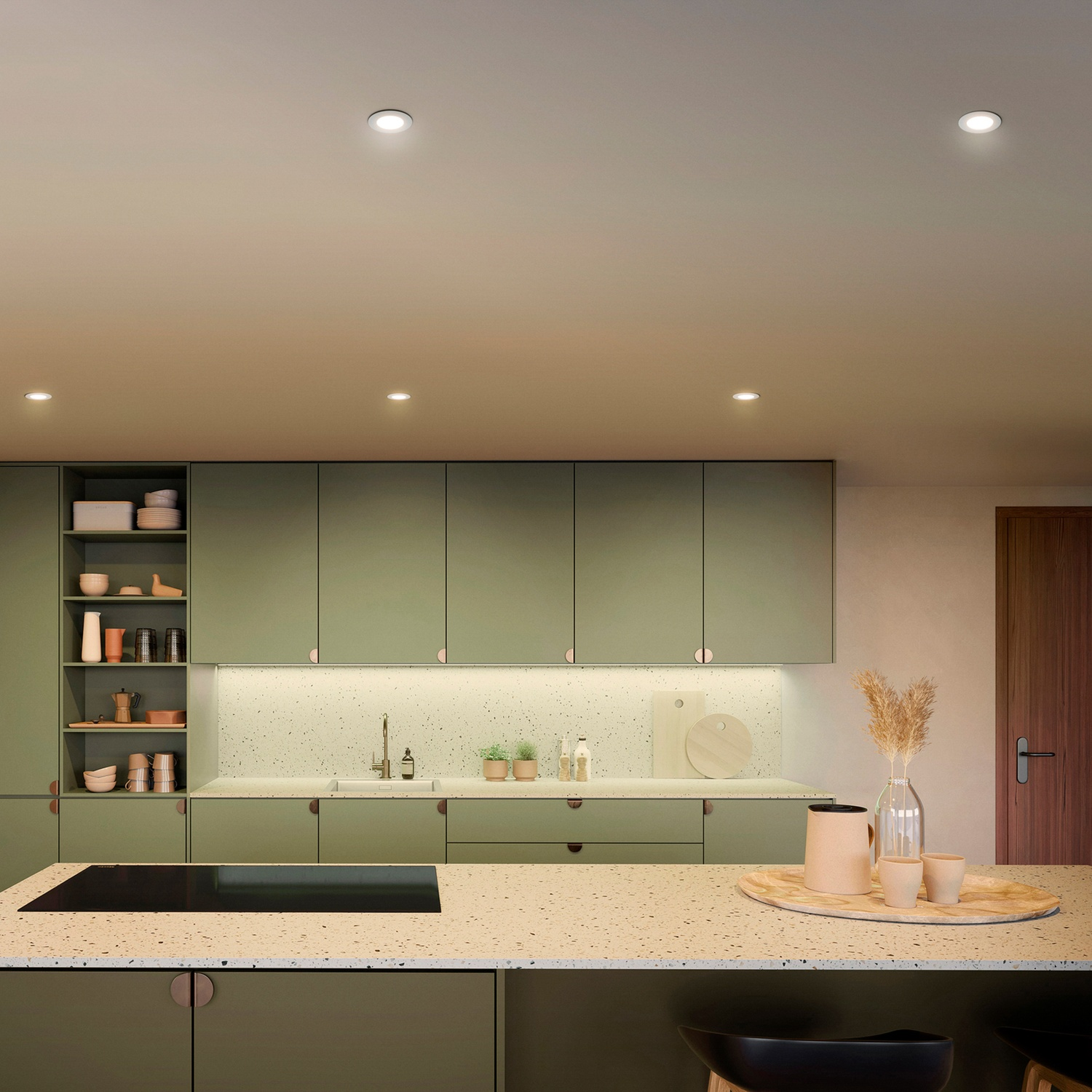 Cuisine moderne avec armoires vert sauge, îlot en terrazzo et porte en bois.