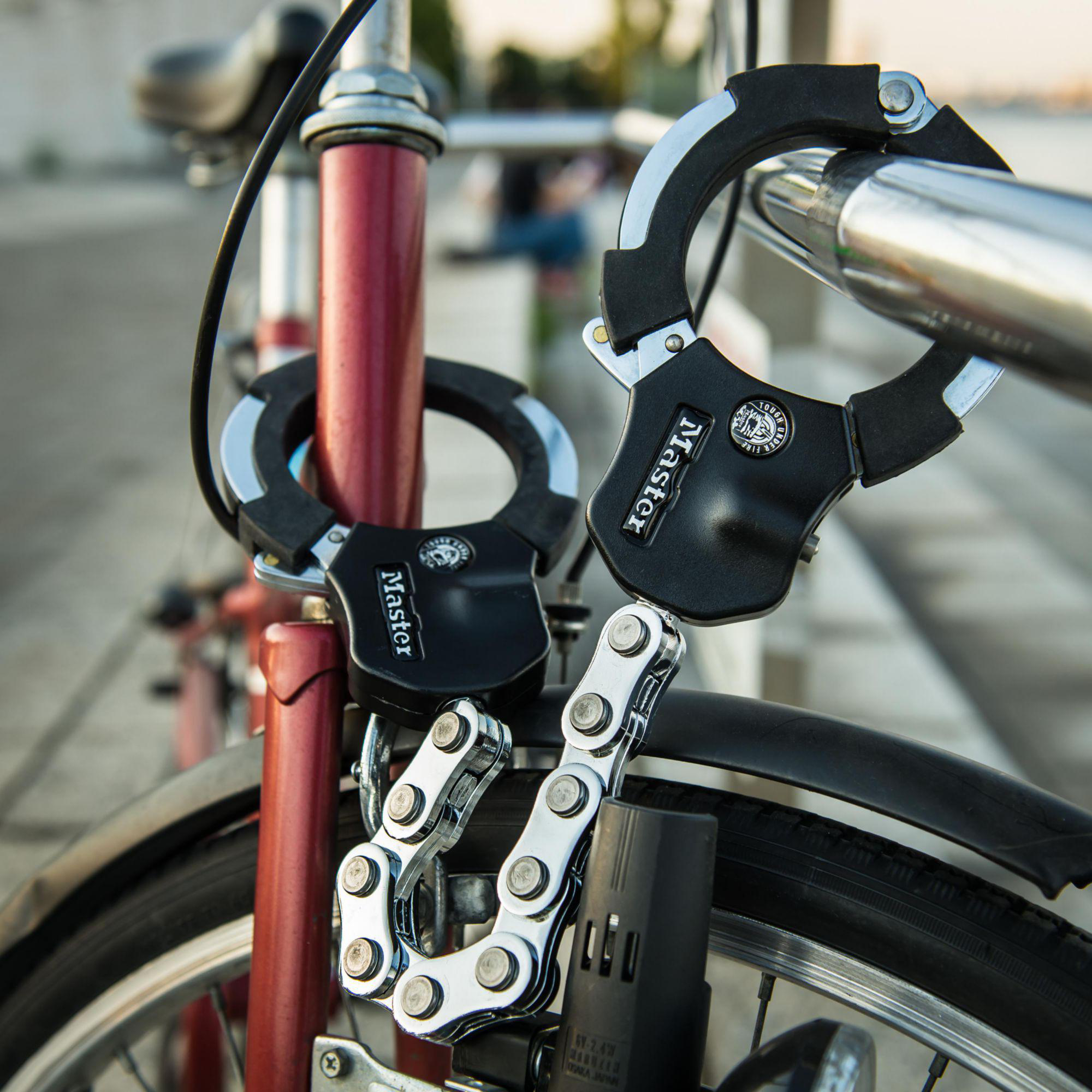 Zwei Fahrradschlösser, ein silberner Ketten- und ein schwarzer Bügel, sind an einem roten Fahrradrahmen befestigt.