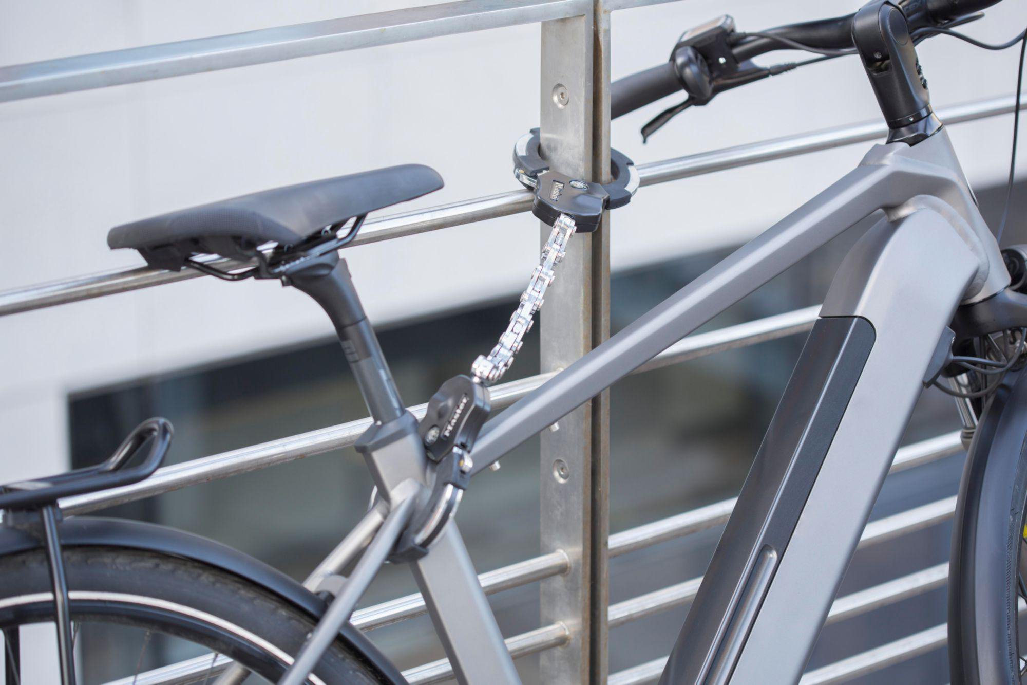 Graues Fahrrad mit Kettenschloss an einem Geländer angeschlossen.