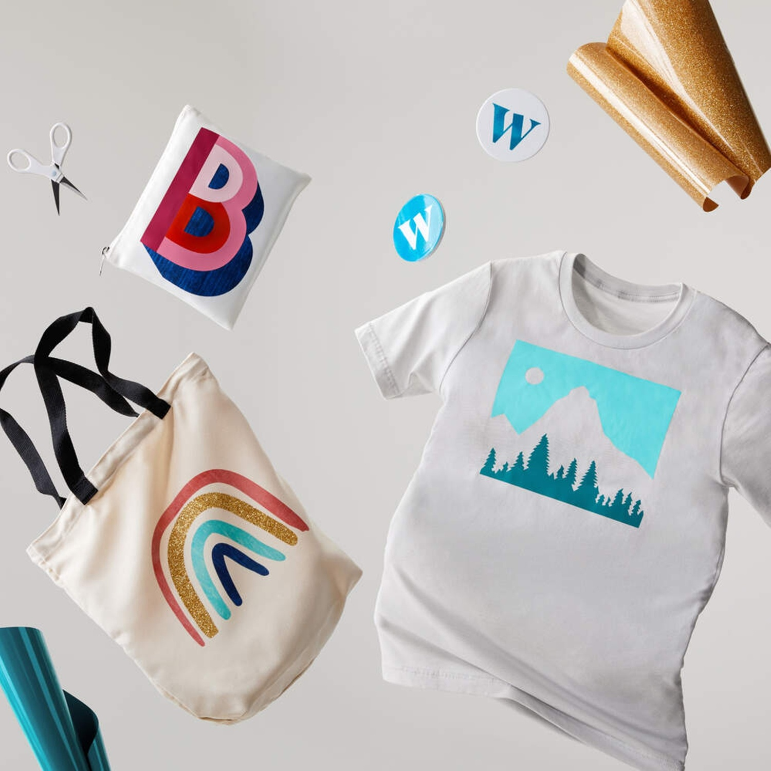 Forbici, pochette con disegno B, rotolo di tessuto, maglietta con disegno montagna, borsa arcobaleno.