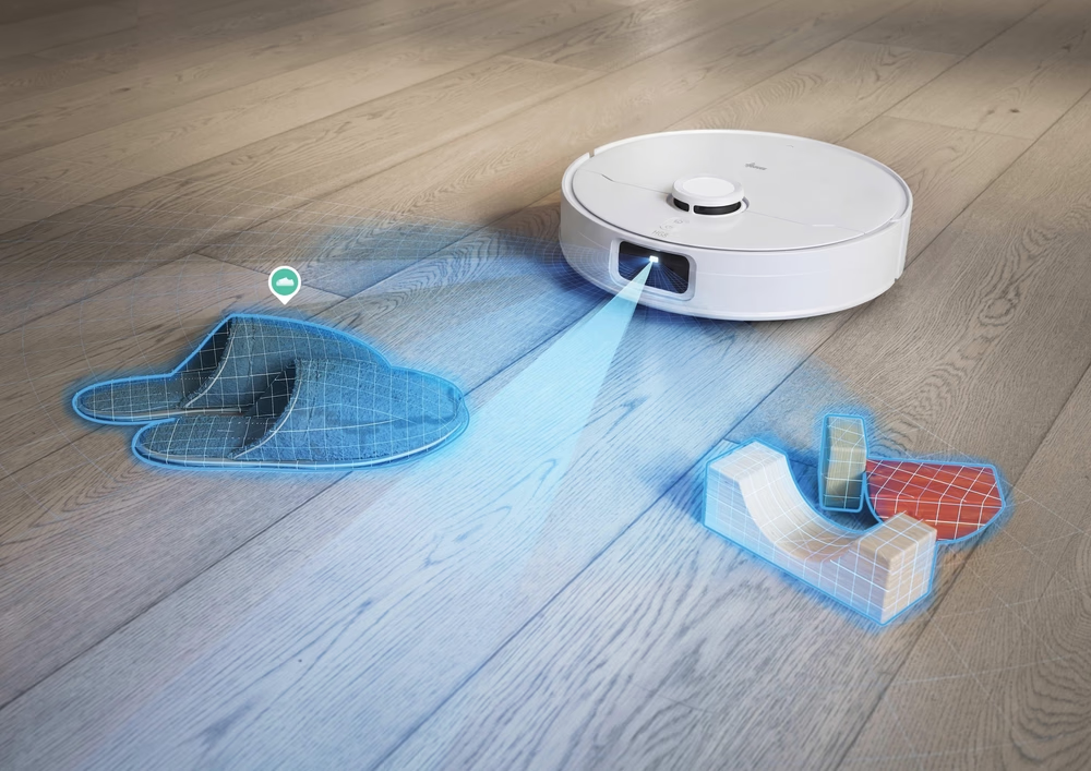 Un robot aspirapolvere bianco scansiona pantofole e giocattoli su pavimento in legno con un raggio blu.