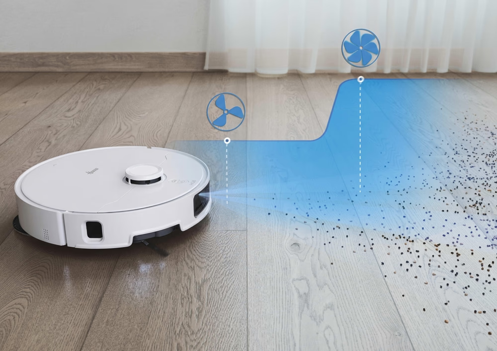 Un robot aspirapolvere bianco pulisce briciole su un pavimento in legno, visualizzato con icone di ventilatori blu.