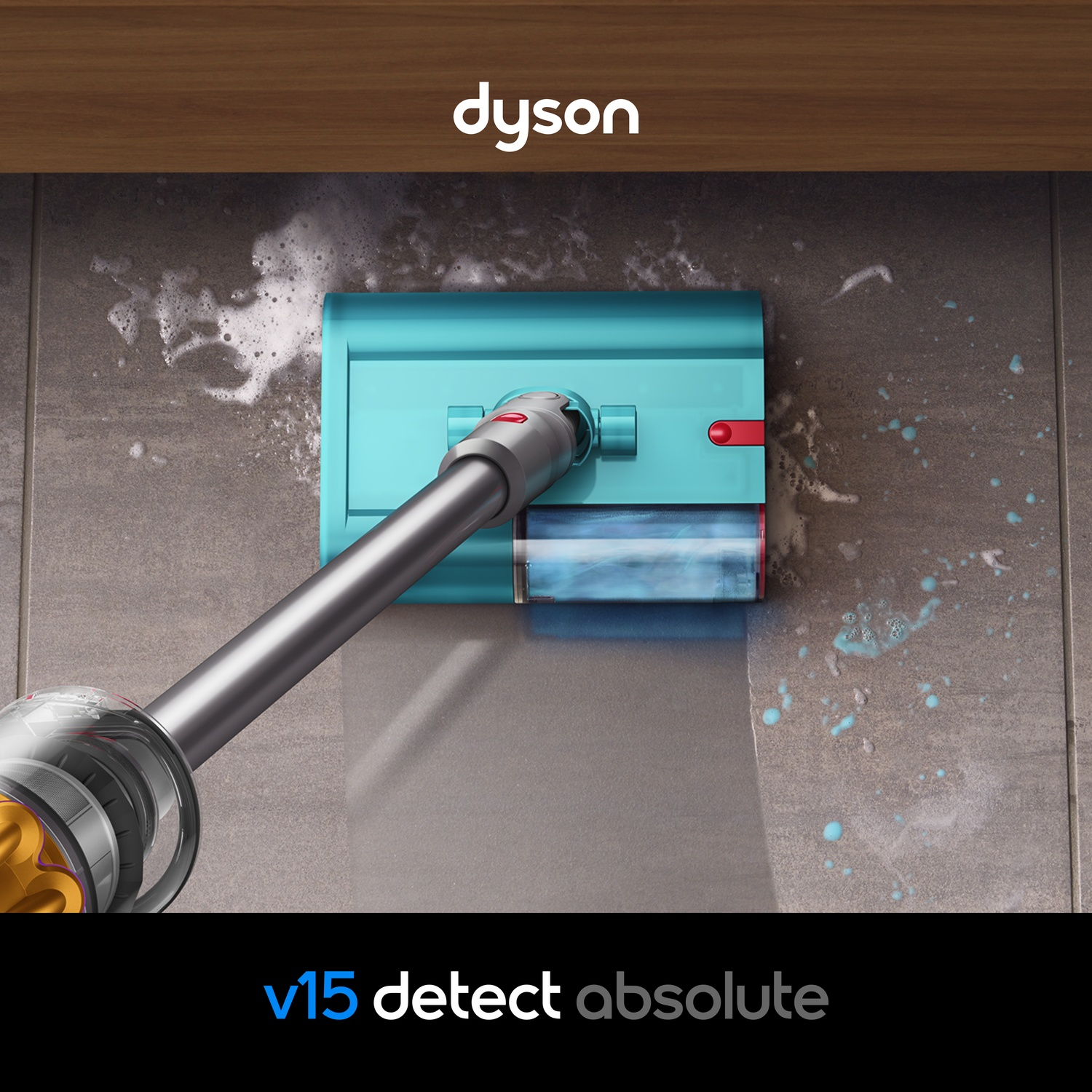 Un nettoyeur Dyson bleu humide/sec serpille sur des carreaux gris avec de la mousse.
