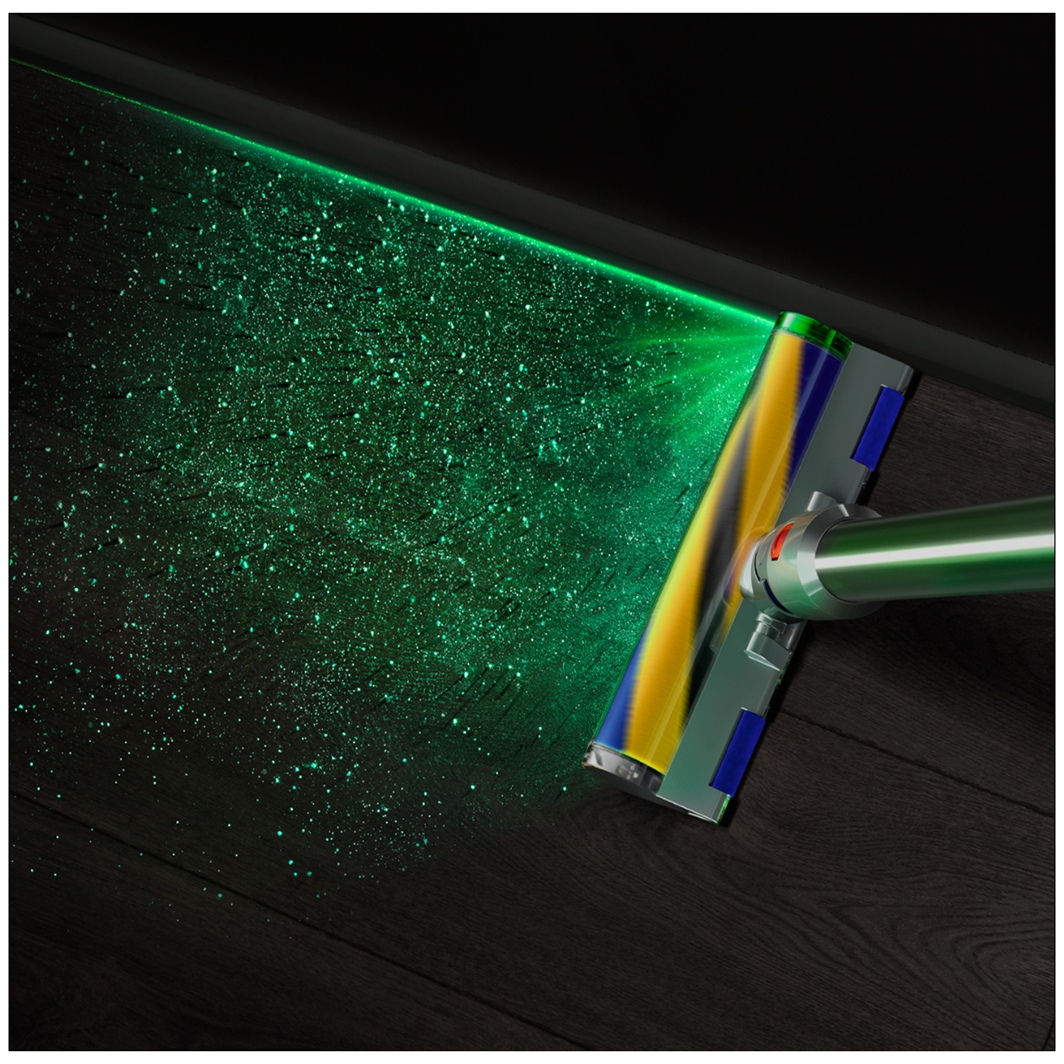 Une tête d'aspirateur avec laser vert illumine des particules de poussière sur un parquet sombre.