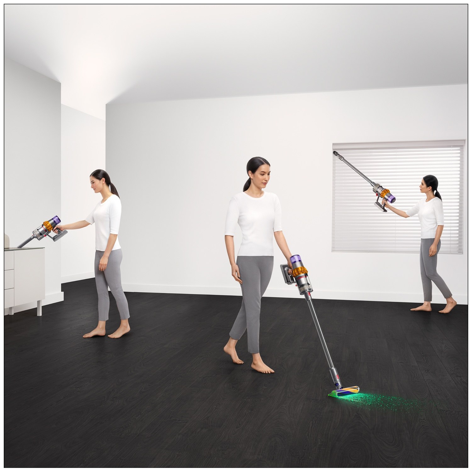 Femme passe l'aspirateur Dyson sur sol bois sombre. Lumière verte éclaire le sol.