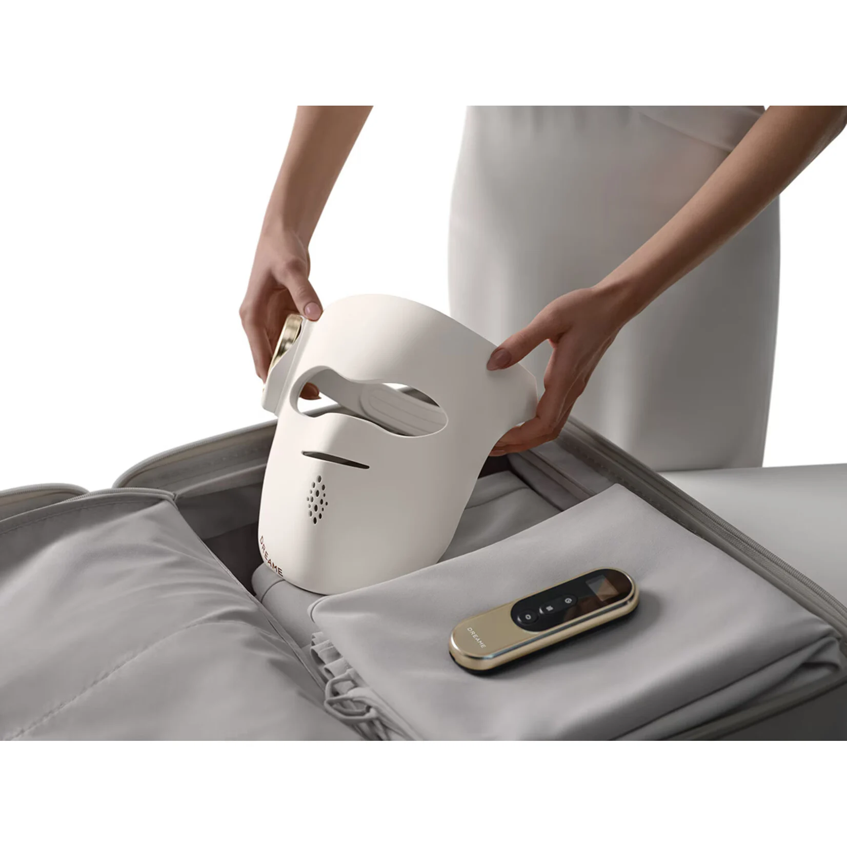 Una mascarilla facial blanca se coloca en una maleta gris.