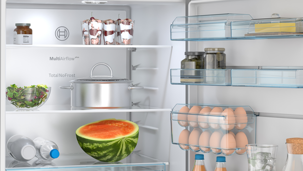 Yiyeceklerle açık buzdolabı: karpuz, salata, yumurta, kavanozlar ve şişeler.
