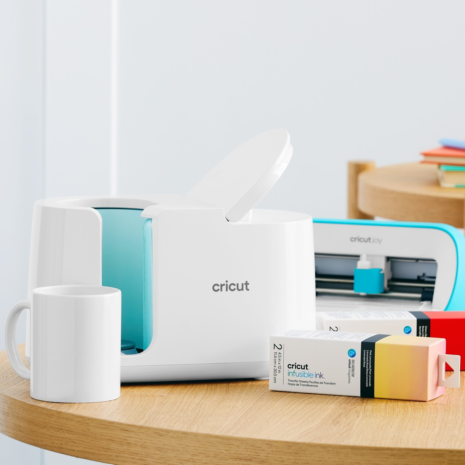 Tazza bianca, Cricut Mug Press e fogli transfer Infusible Ink su tavolo di legno.
