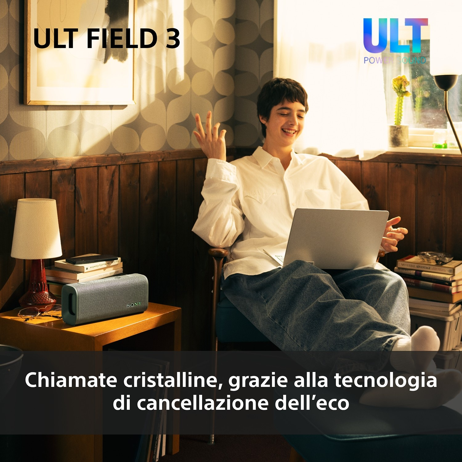 Una persona con laptop seduta su una sedia accanto a uno speaker e un tavolo.