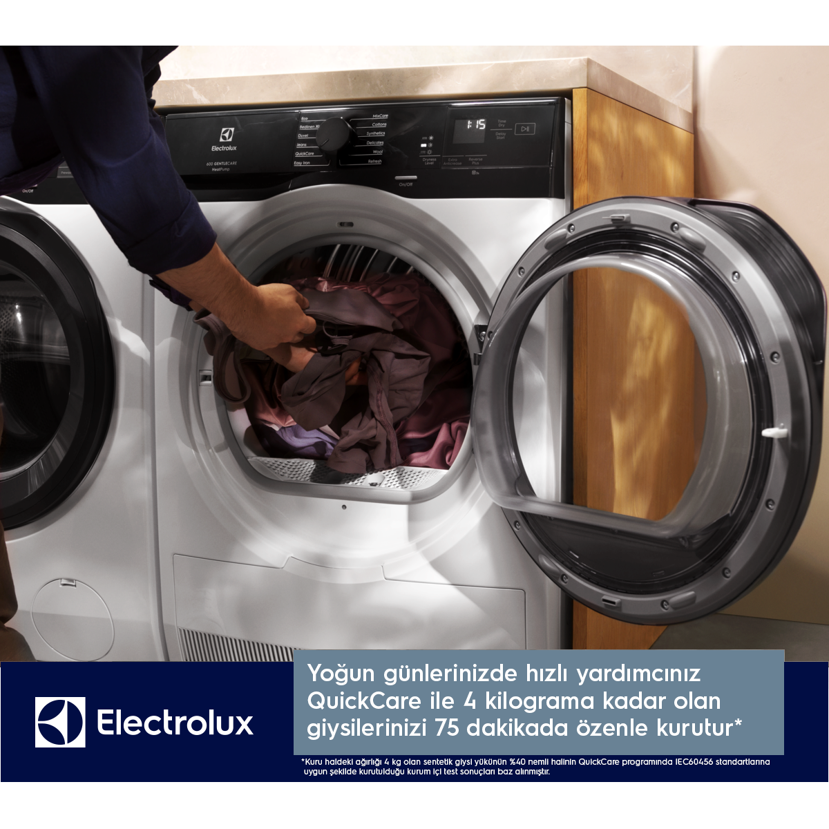 Bir kişi açık Electrolux kurutma makinesine çamaşır yüklüyor.
