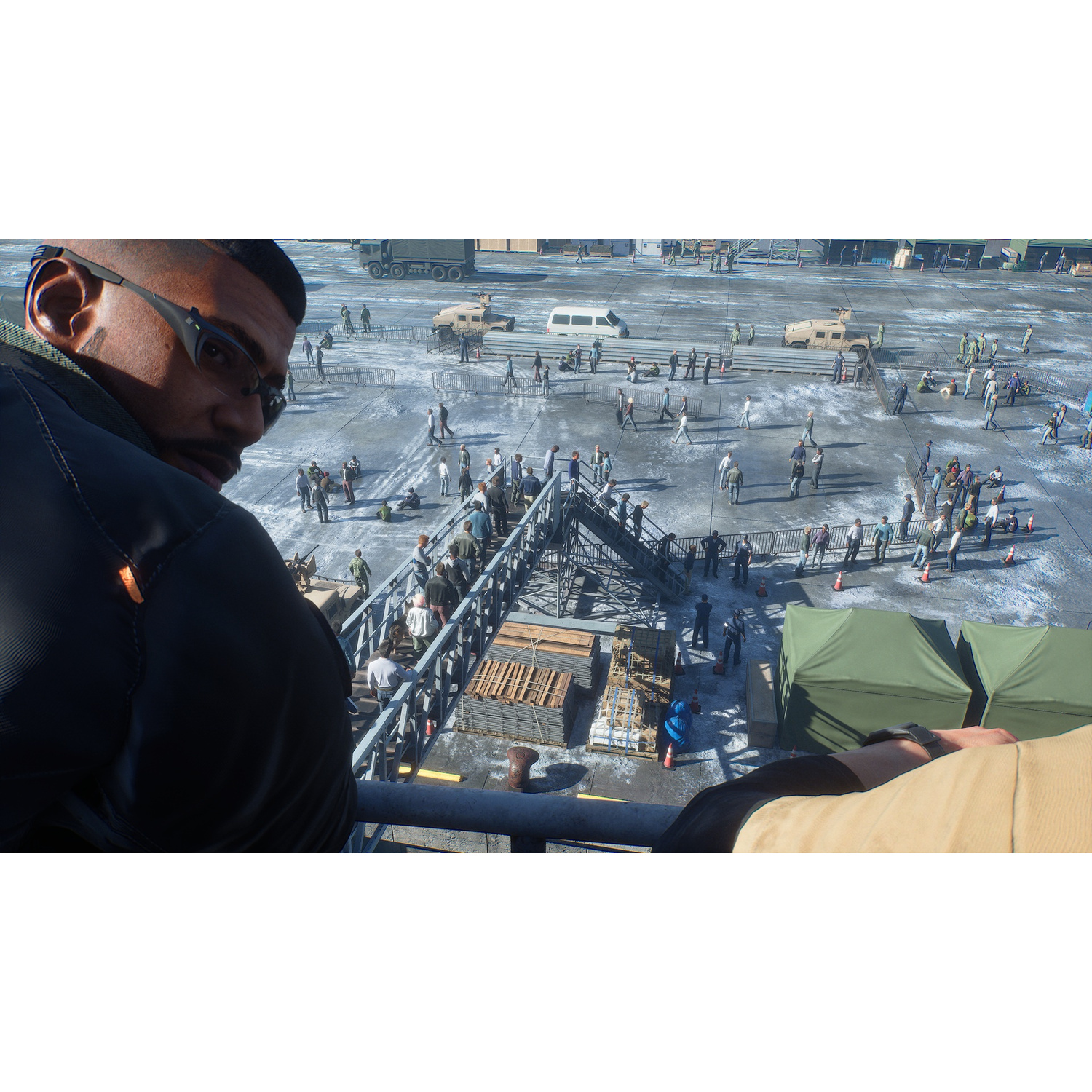 Un uomo con gli occhiali guarda una folla di persone e veicoli militari.