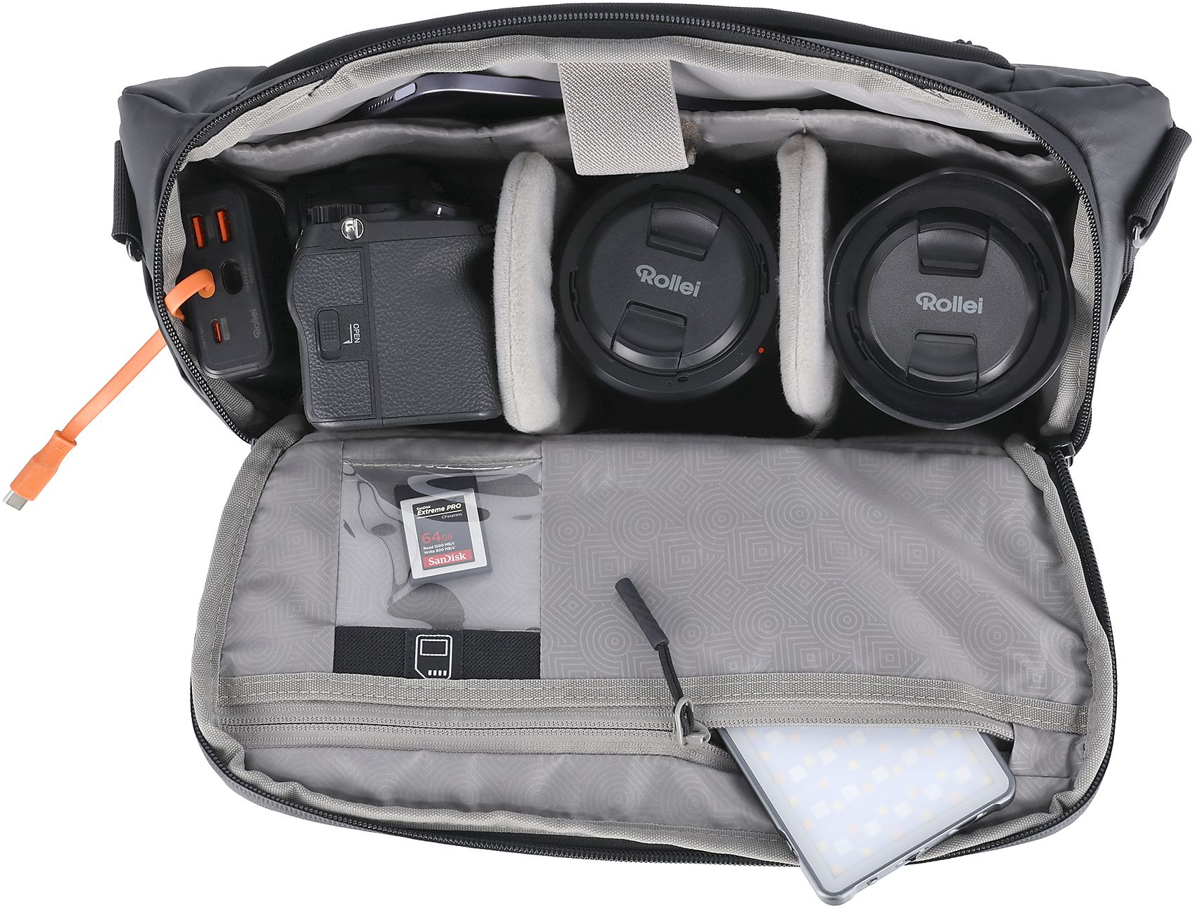 Un sac photo noir avec équipement : appareil photo, objectifs, cartes mémoire et câble de chargement.