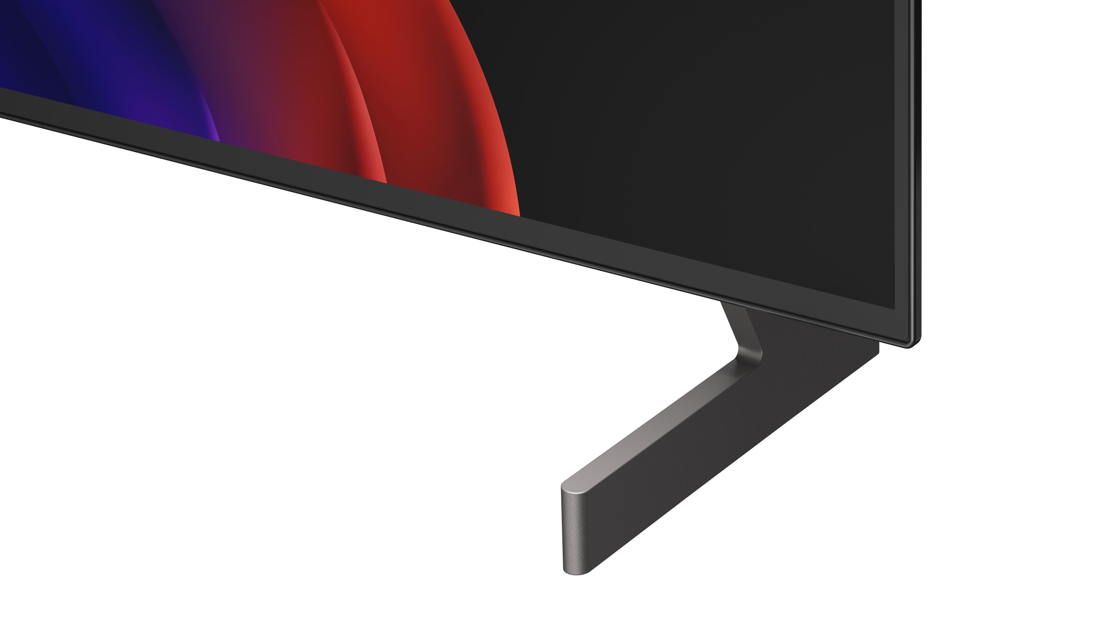 Untere Ecke eines Fernsehers mit einem schmalen, dunklen Standfuß und einem abstrakten Hintergrund.