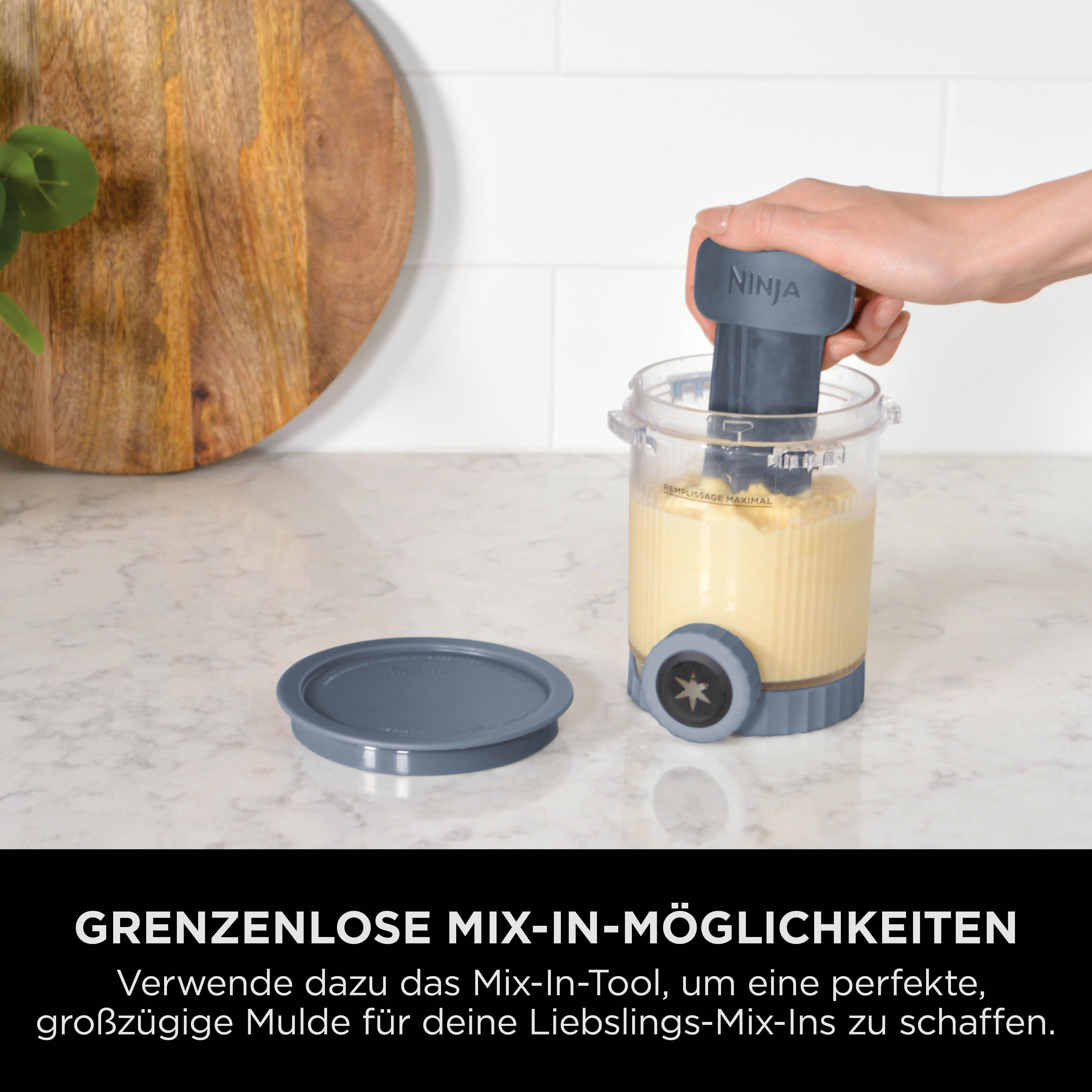 Hand hält Ninja Mix-In-Tool in gelbem Behälter. Deckel daneben.