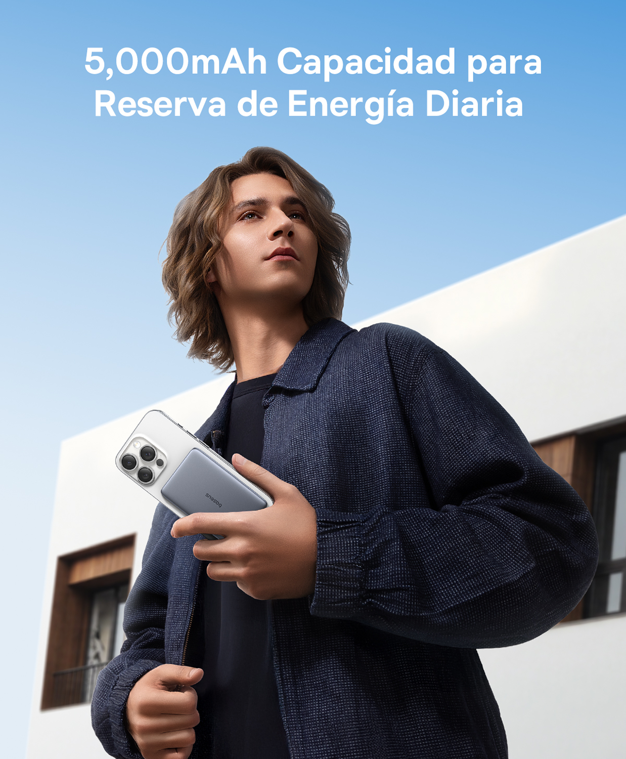 Un joven sostiene un smartphone con un estuche de carga acoplado frente a un edificio.