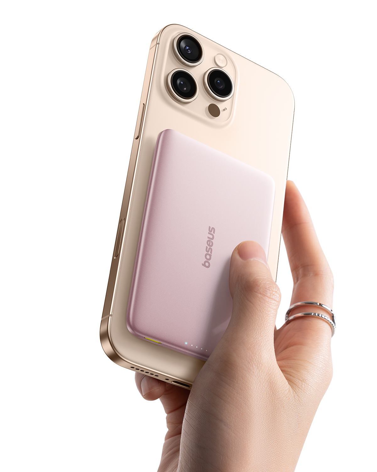 Una mano sostiene un iPhone dorado con una batería externa magnética rosa.