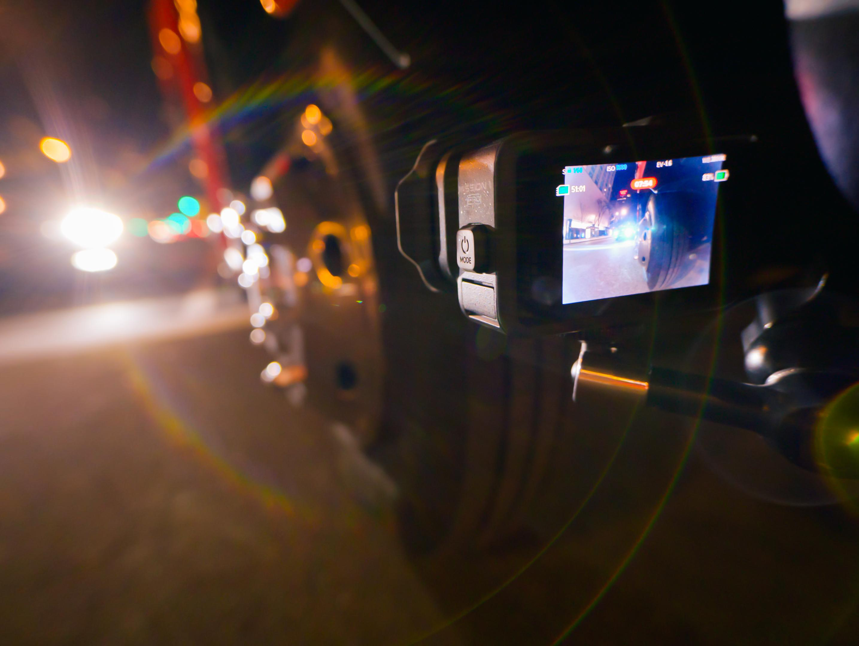 Eine Action-Kamera zeichnet eine nächtliche Straßenszene auf, mit Lichtern und Bokeh.