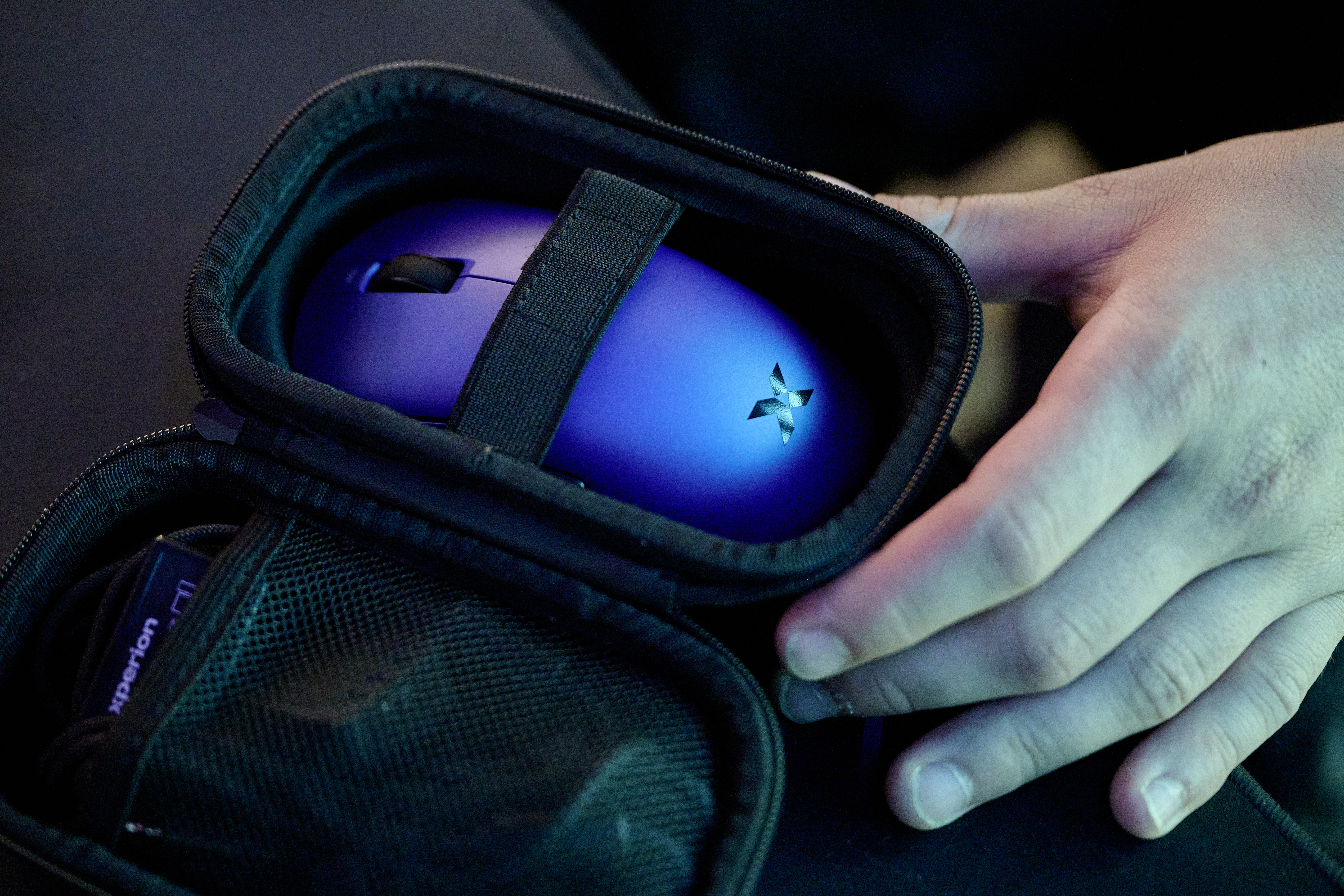 Eine Person legt eine blaue Computermouse in eine schwarze Tasche.