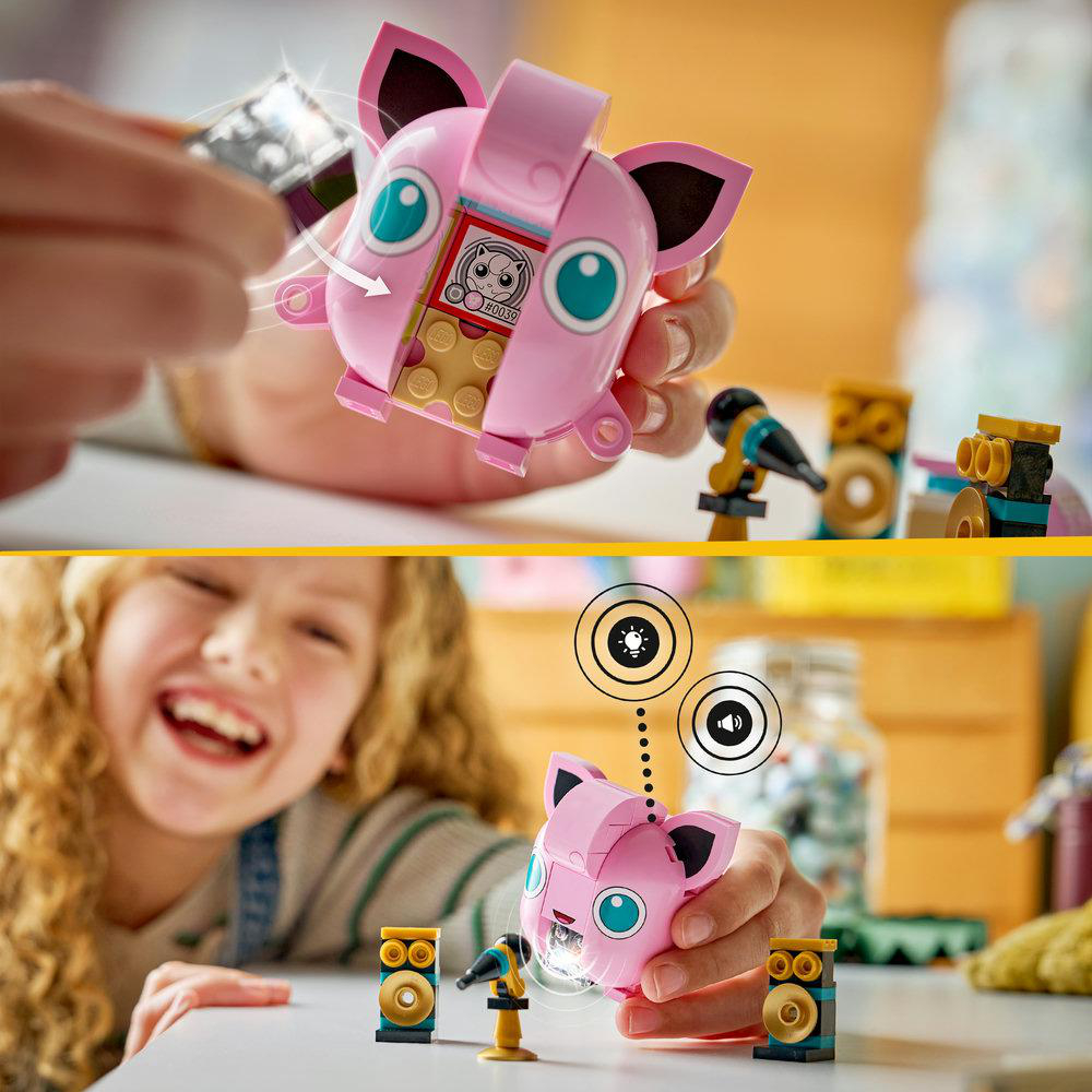 Kinderhände interagieren mit einem pinken Jigglypuff-Spielzeug mit Lautsprecher und Mikrofon, Licht strahlt vom Spielzeug aus.