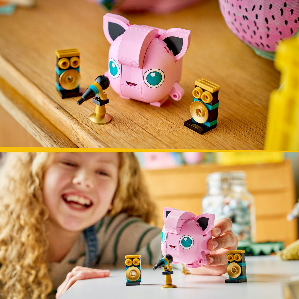 Rosa Pokémon-Figur mit Mikrofon und Lautsprechern auf Holz; ein Mädchen hält es.