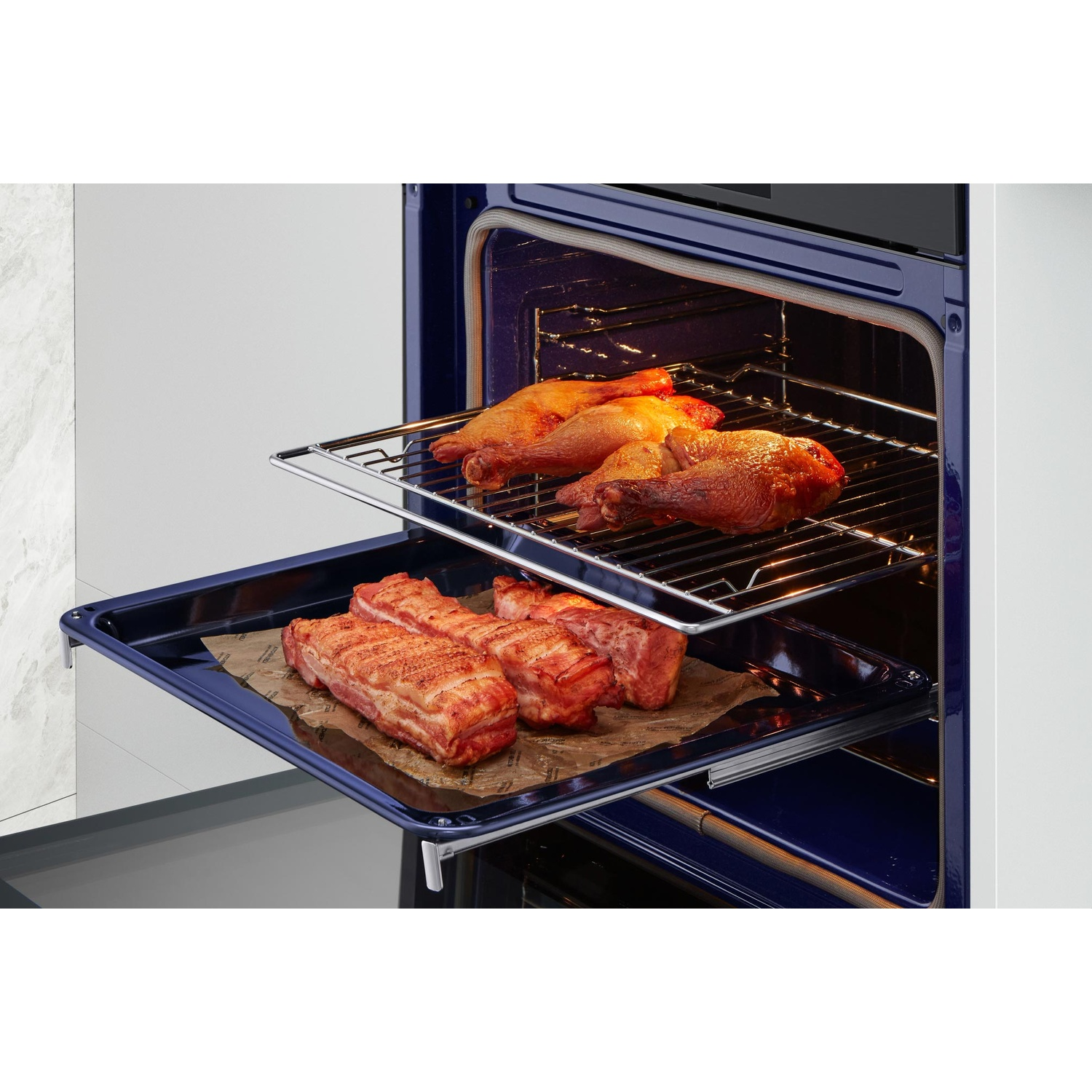 Pezzi di carne cruda su una teglia e cosce di pollo su una griglia all'interno di un forno.