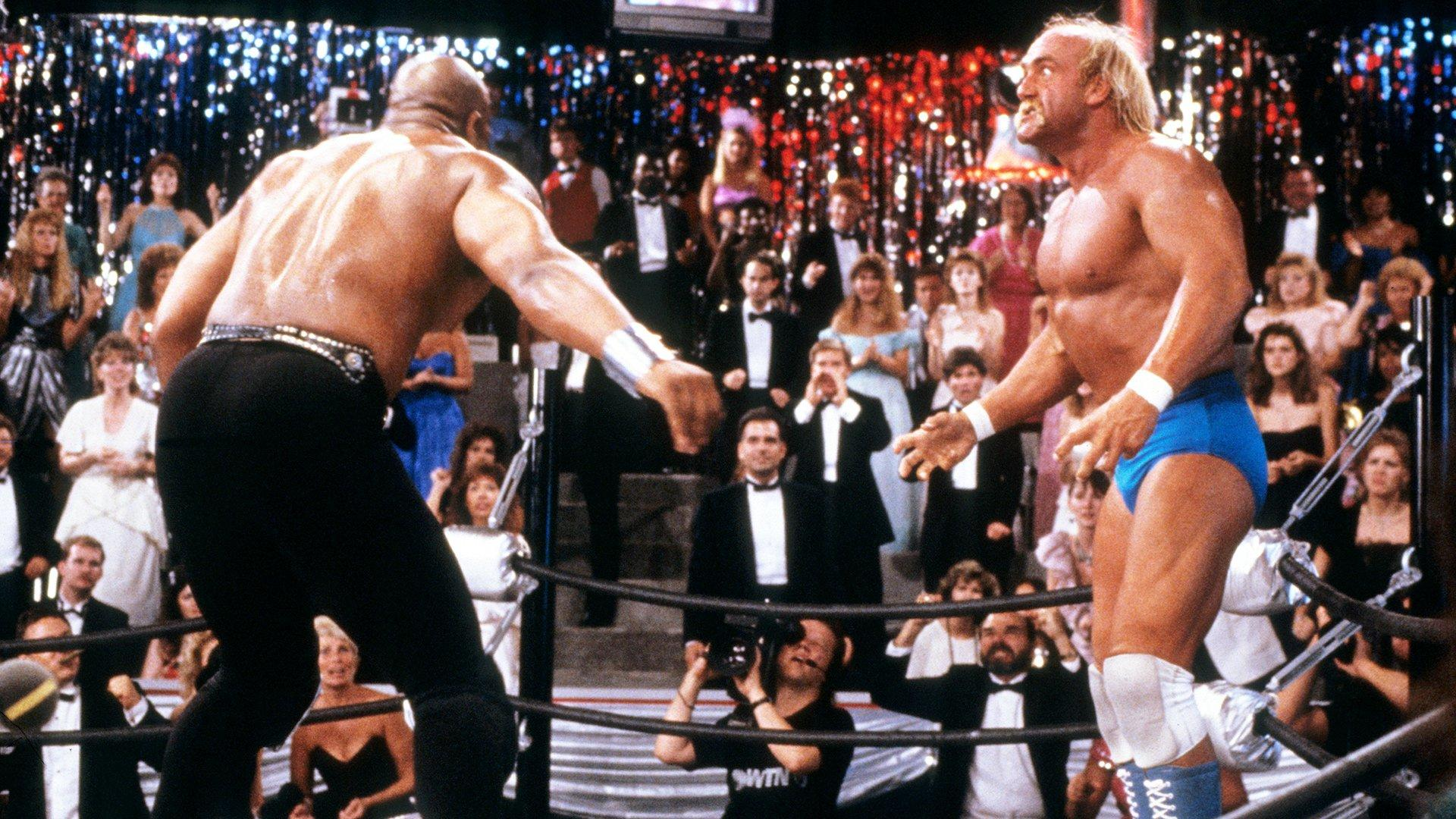 Zwei Wrestler im Ring, umgeben von jubelnden Zuschauern in festlicher Kleidung.