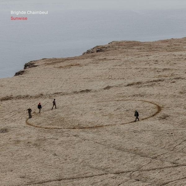 Menschen gehen auf einem trockenen Feld in der Nähe des Meeres, ein Kreis ist auf dem Boden gezeichnet.