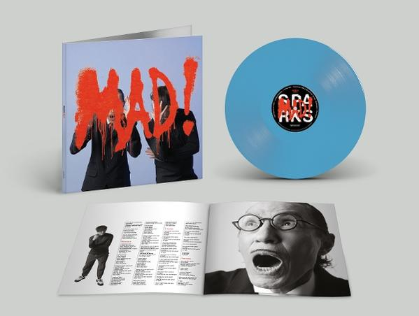 Ein blaues Vinyl, ein geöffnetes Album mit Bildern und Texten. Frontcover mit zwei Personen und rotem Schriftzug.