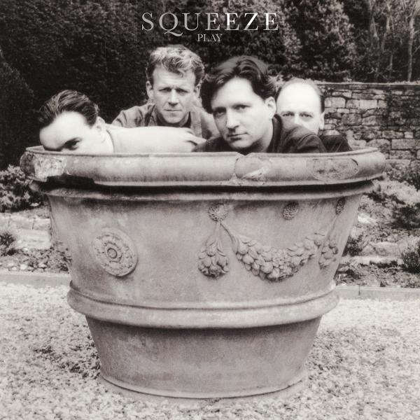 Vier Männer stecken in einem großen Steinpflanzgefäß. Der Bandname Squeeze ist oben.