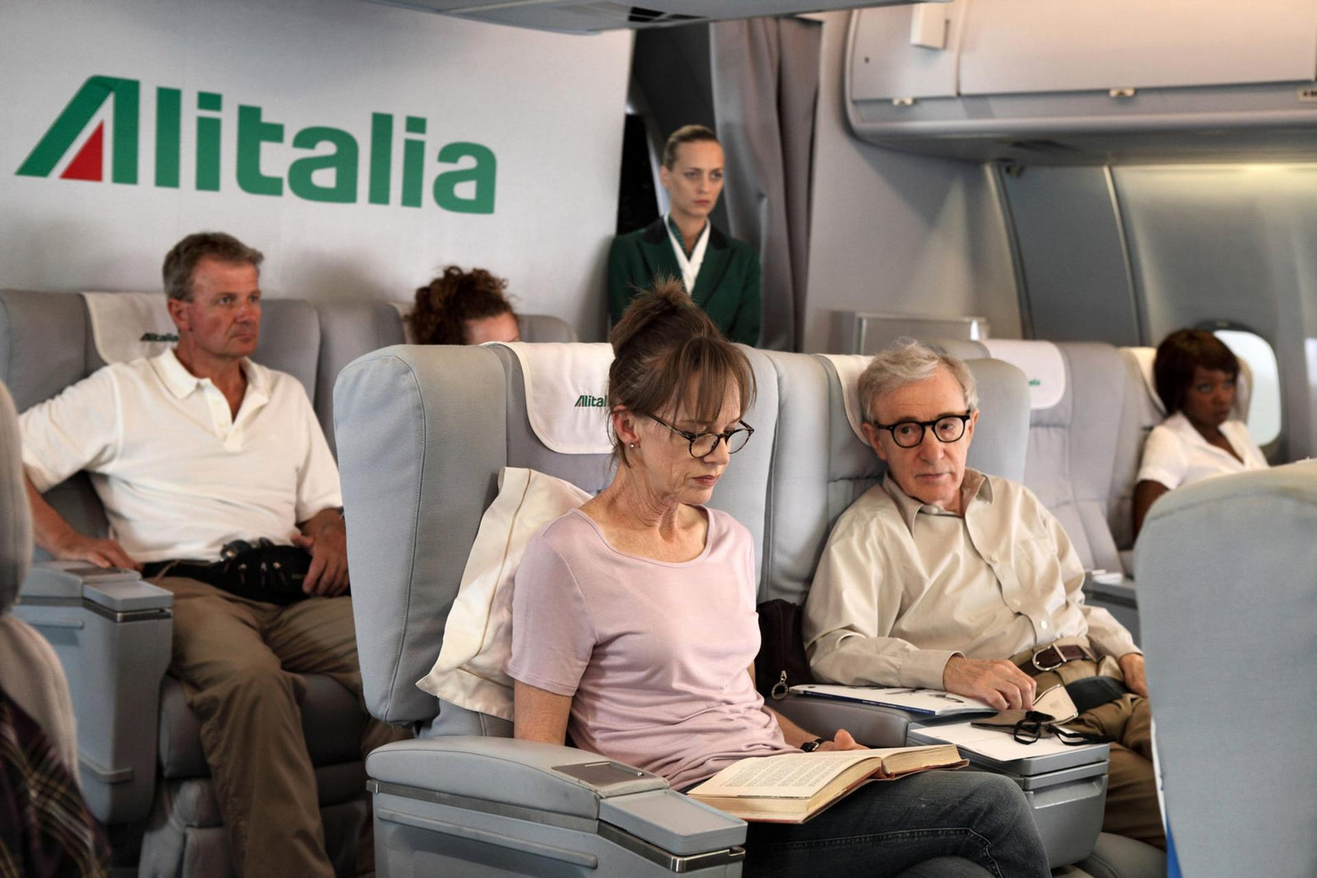 Passagiere in einem Alitalia-Flugzeug, darunter Woody Allen, lesen und sitzen.