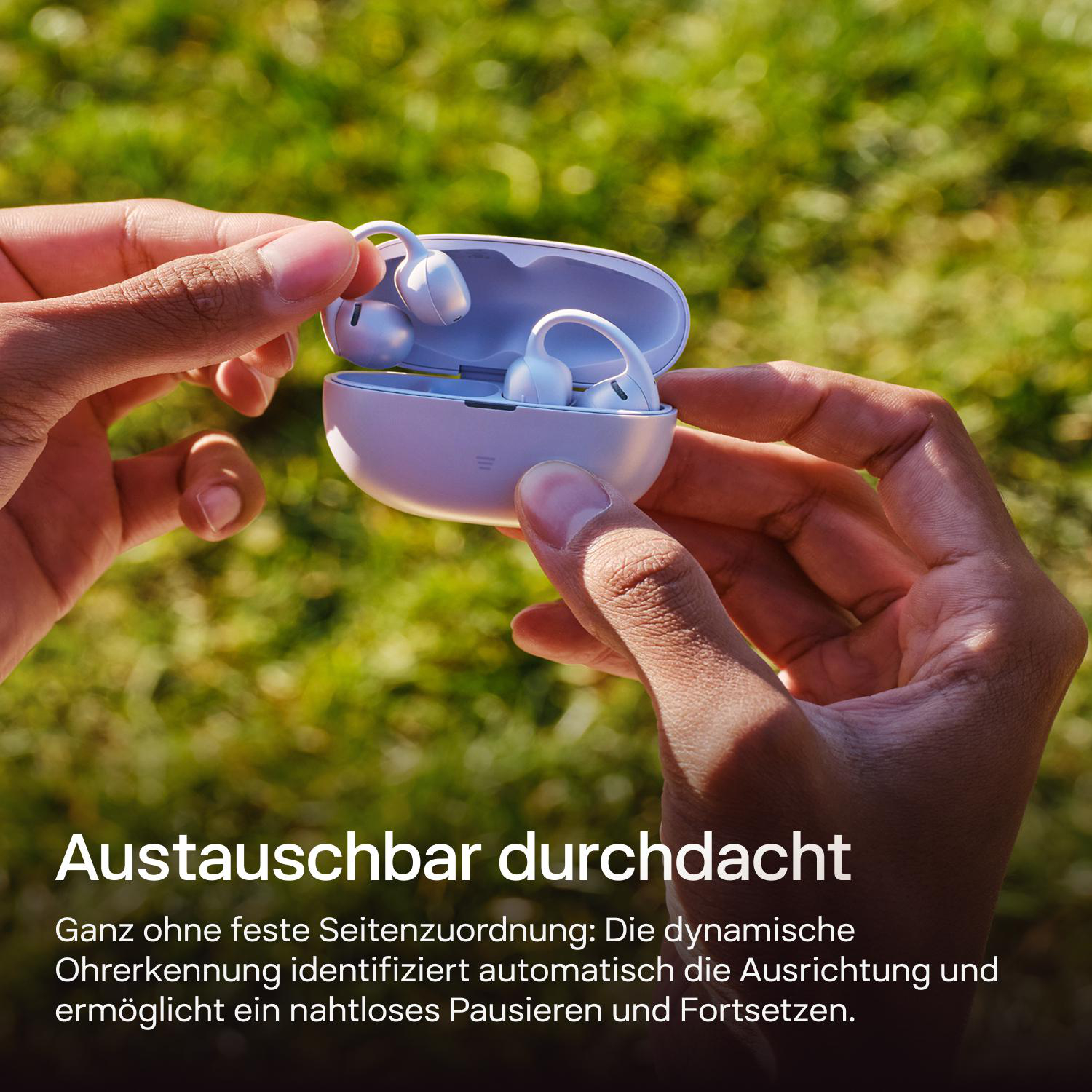 Hände halten ein hellviolettes Etui mit weißen Ohrhörern. Draußen.